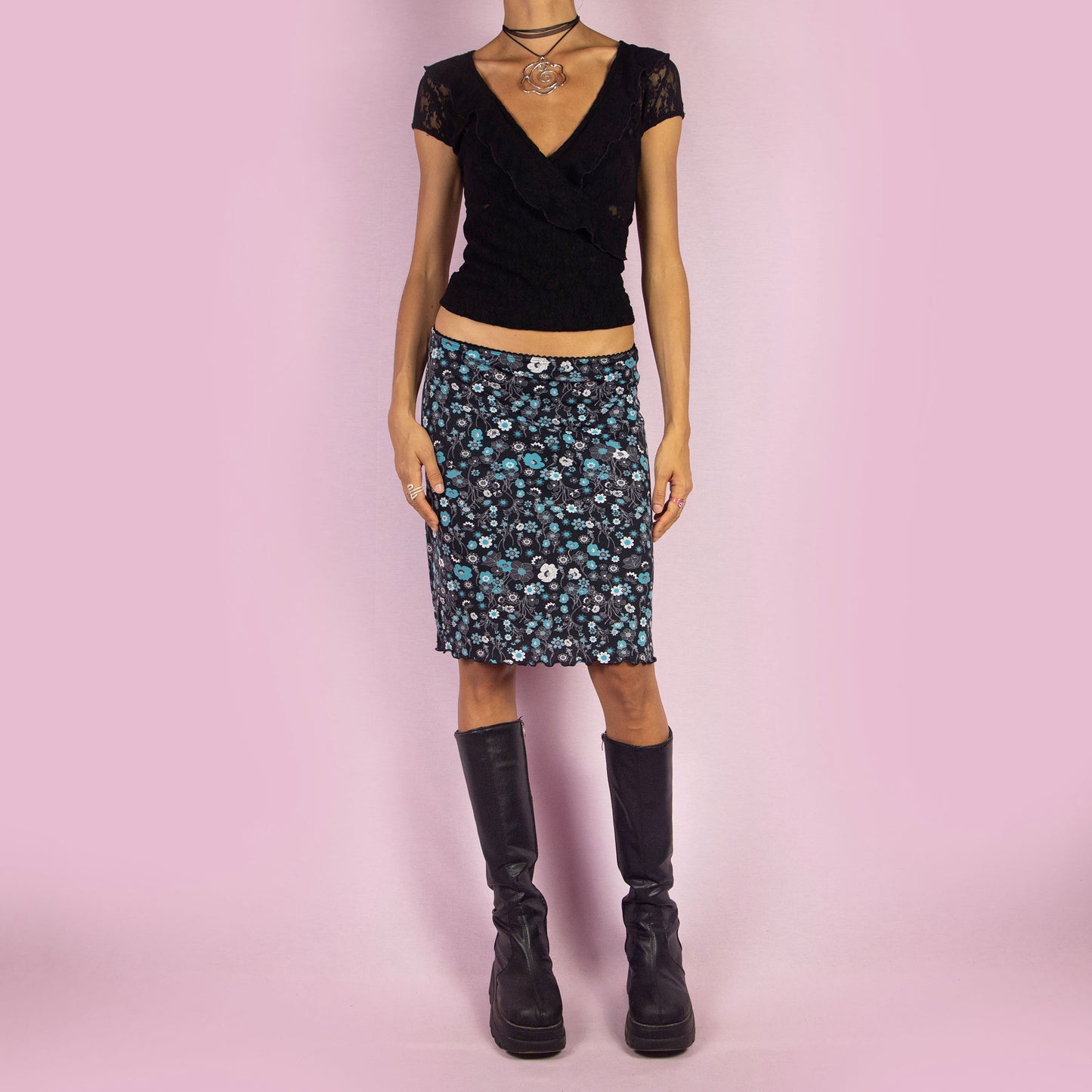 The Y2K Black Floral Mini Skirt is a vintage 2000s piece featuring a playful floral print in black and blue, with an elastic waist. It has a flattering high-waisted A-line silhouette, making it perfect for summer days or casual outings.
