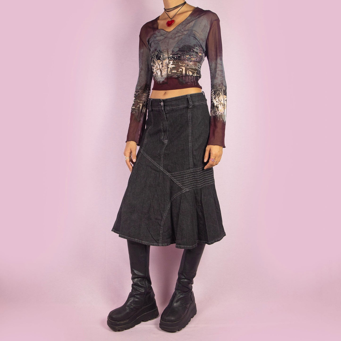 The Y2K Trumpet Dark Denim Skirt is a vintage 2000s piece featuring a high-waist design with a front zipper and button closure. The skirt is crafted from a stretchy black-grayish denim with panelled construction and white contrast stitching, creating a flattering trumpet silhouette. Perfect for casual, everyday looks.