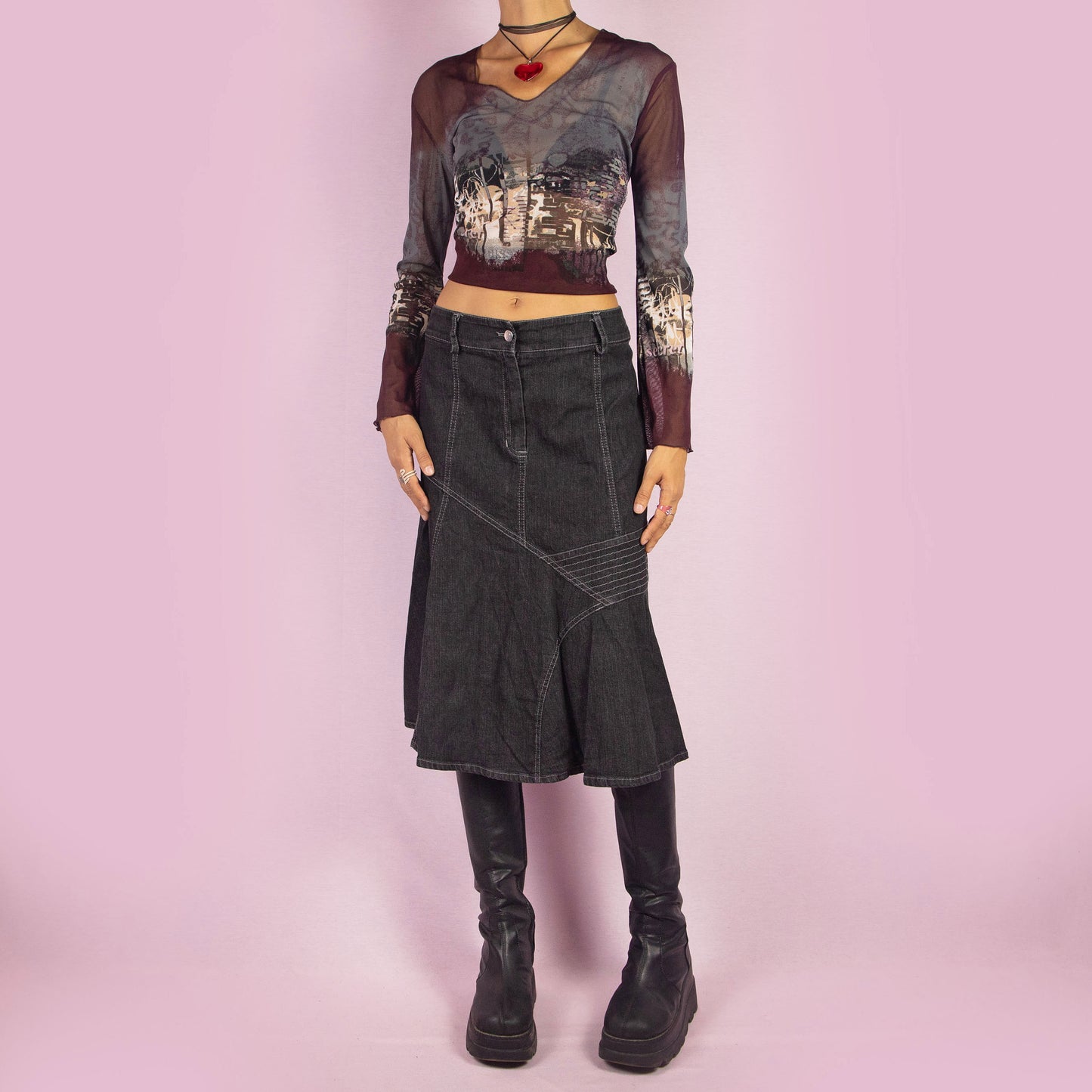 The Y2K Trumpet Dark Denim Skirt is a vintage 2000s piece featuring a high-waist design with a front zipper and button closure. The skirt is crafted from a stretchy black-grayish denim with panelled construction and white contrast stitching, creating a flattering trumpet silhouette. Perfect for casual, everyday looks.