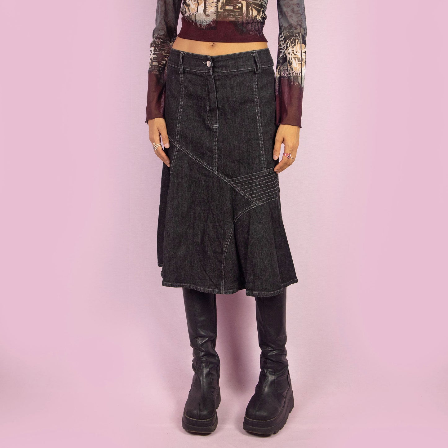 The Y2K Trumpet Dark Denim Skirt is a vintage 2000s piece featuring a high-waist design with a front zipper and button closure. The skirt is crafted from a stretchy black-grayish denim with panelled construction and white contrast stitching, creating a flattering trumpet silhouette. Perfect for casual, everyday looks.