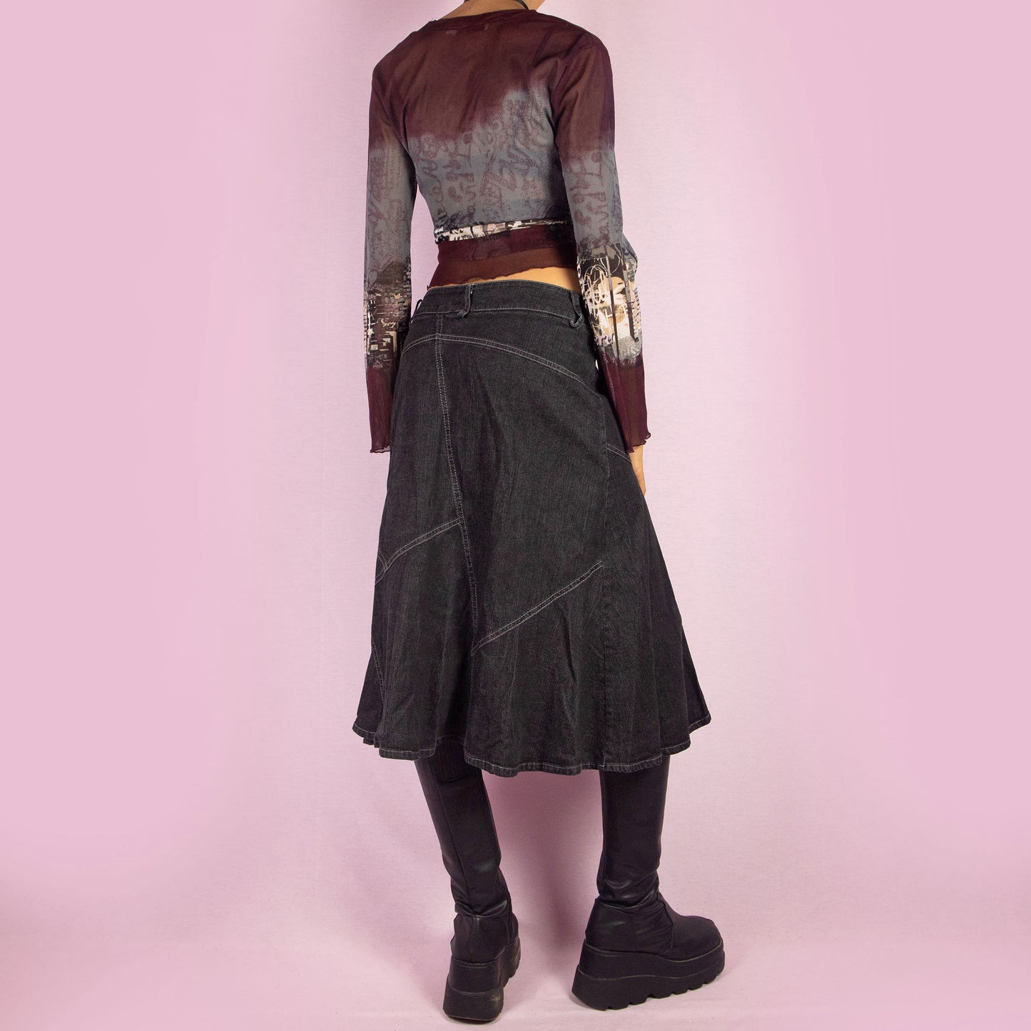 The Y2K Trumpet Dark Denim Skirt is a vintage 2000s piece featuring a high-waist design with a front zipper and button closure. The skirt is crafted from a stretchy black-grayish denim with panelled construction and white contrast stitching, creating a flattering trumpet silhouette. Perfect for casual, everyday looks.