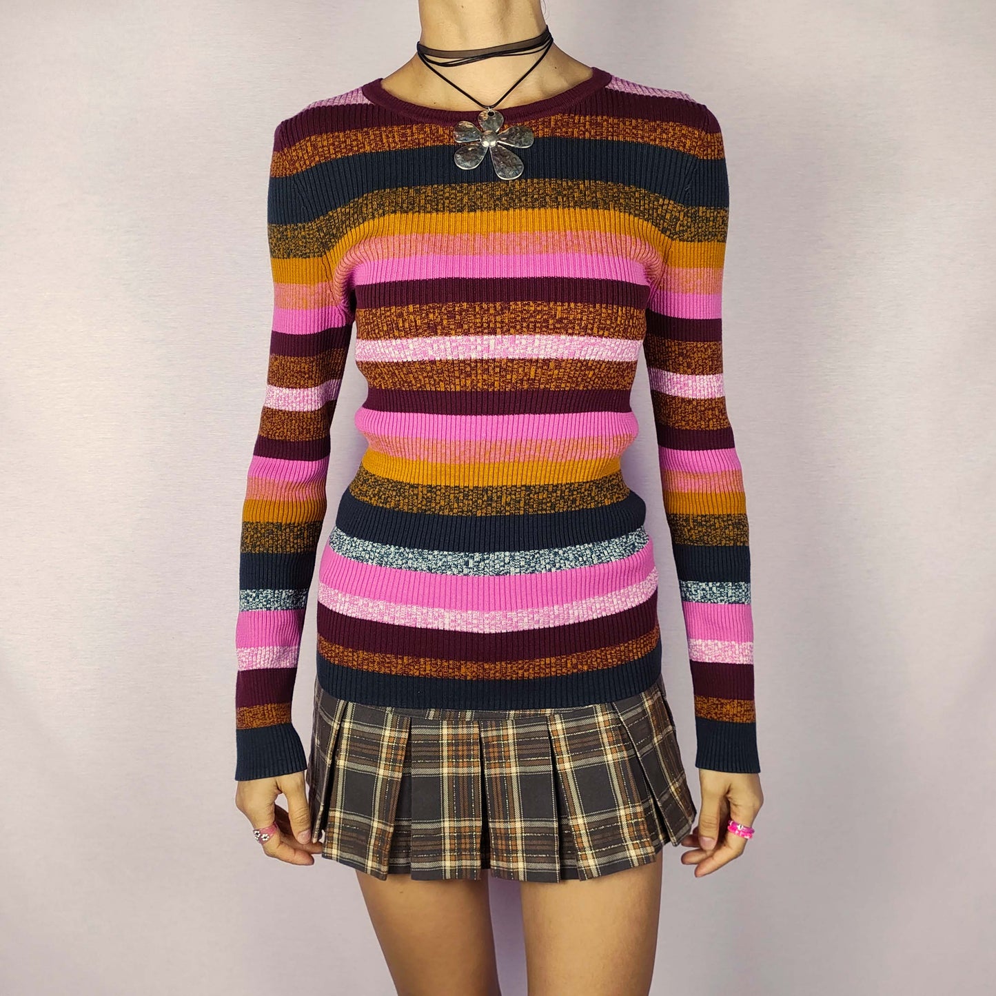 The Y2K Striped Ribbed Sweater is a cozy vintage 2000s piece featuring multicolored horizontal stripes in shades of pink, mustard, burgundy, and dark navy. This fitted sweater is ribbed for a stretchy, comfortable feel, making it a perfect addition for casual autumn and winter looks.