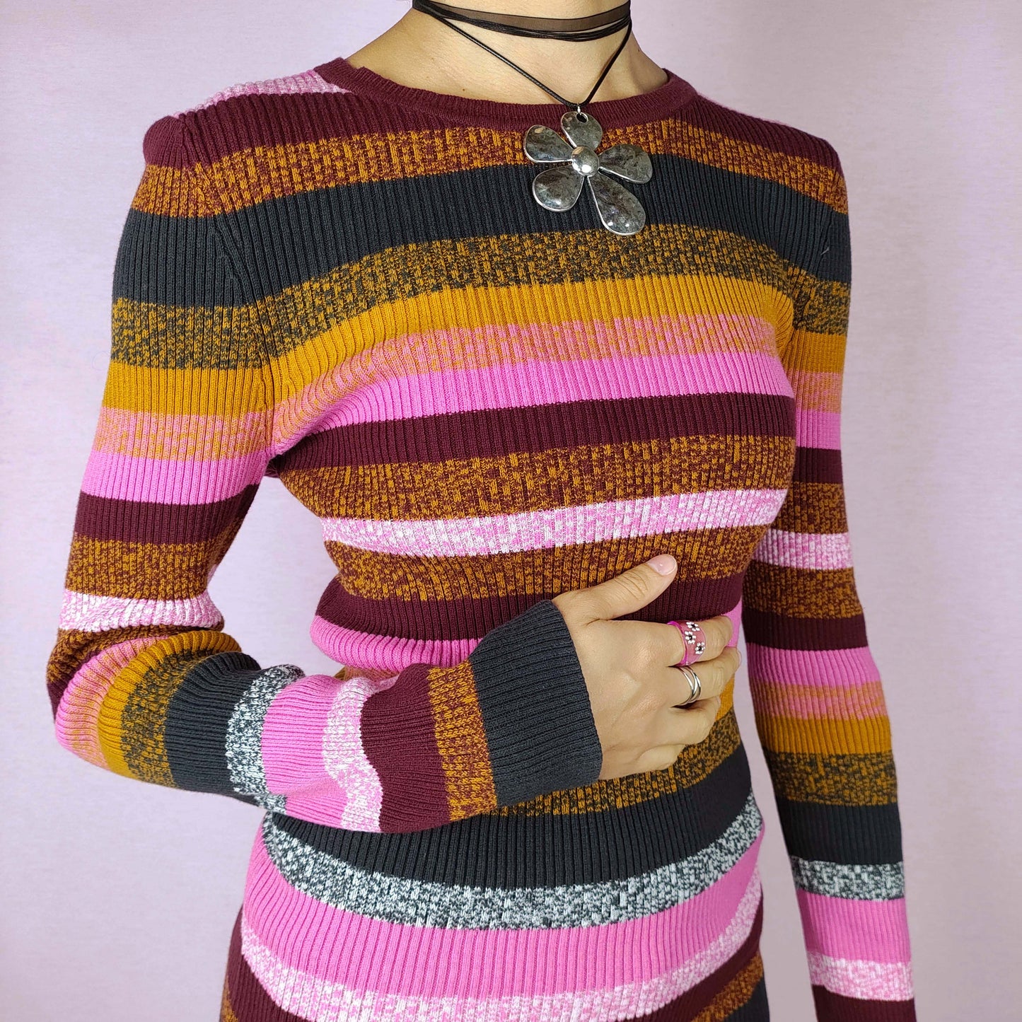 The Y2K Striped Ribbed Sweater is a cozy vintage 2000s piece featuring multicolored horizontal stripes in shades of pink, mustard, burgundy, and dark navy. This fitted sweater is ribbed for a stretchy, comfortable feel, making it a perfect addition for casual autumn and winter looks.