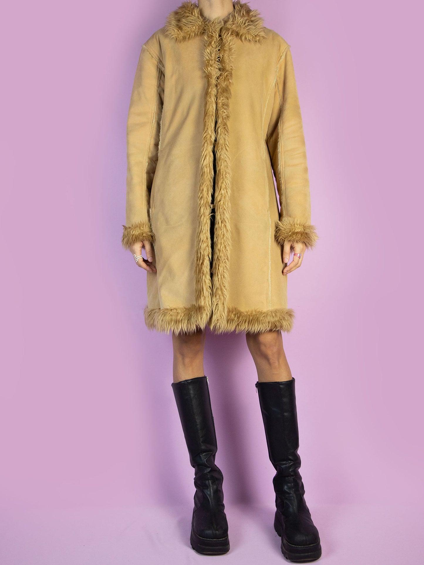 The Y2K Penny Lane Beige Coat is a vintage 2000s light brown-beige faux suede coat featuring a faux fur interior, collar, and cuffs. Equipped with pockets and a hook closure, this boho-inspired overcoat is perfect for a casual and cozy winter outfit.