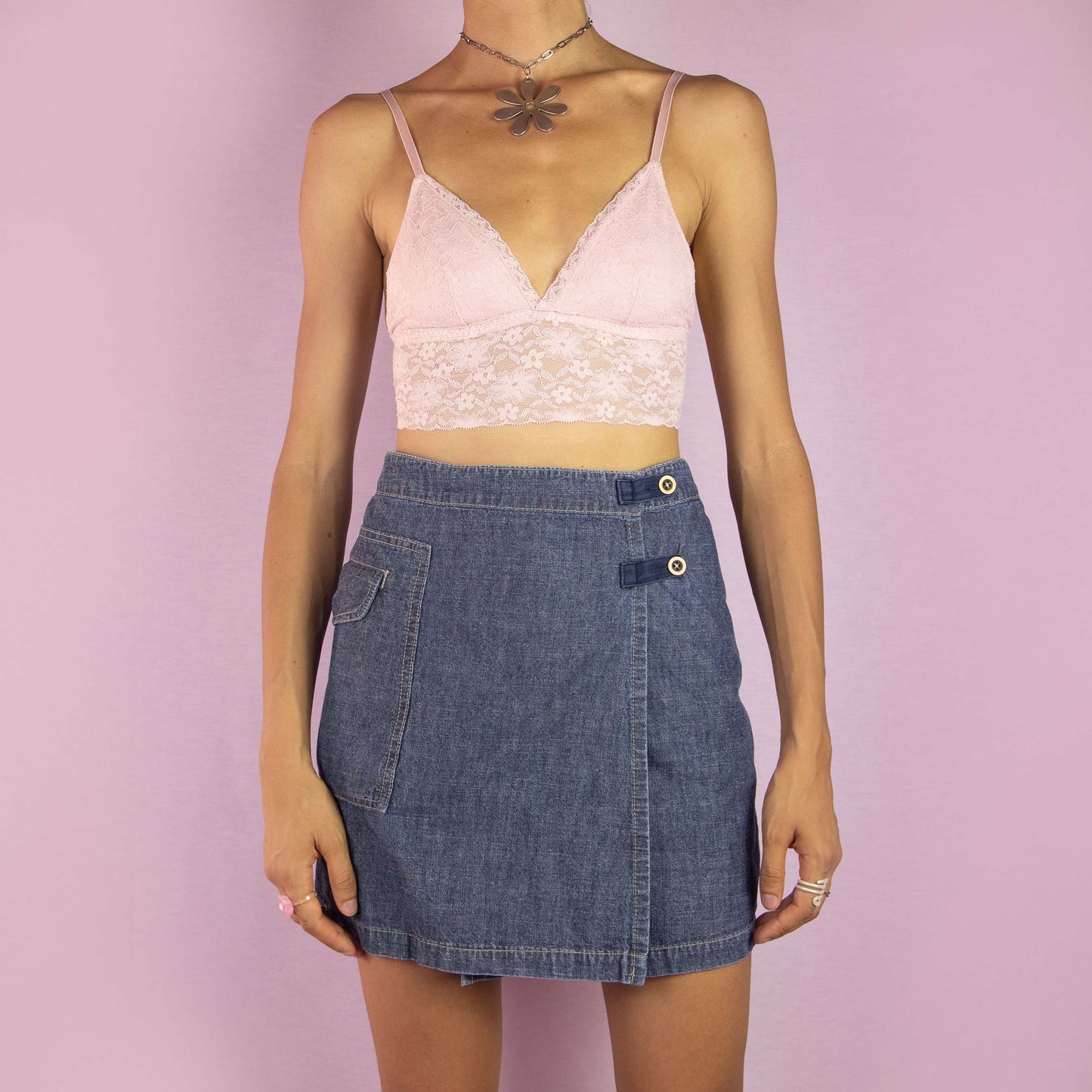 The Y2K Denim Wrap Mini Skirt is a vintage 2000s piece featuring a mid-rise fit and a unique wrap-style design with built-in shorts underneath. Made from medium-wash denim, the skirt has an asymmetrical front with button detailing and a side pocket. Ideal for casual wear and summer outings.
