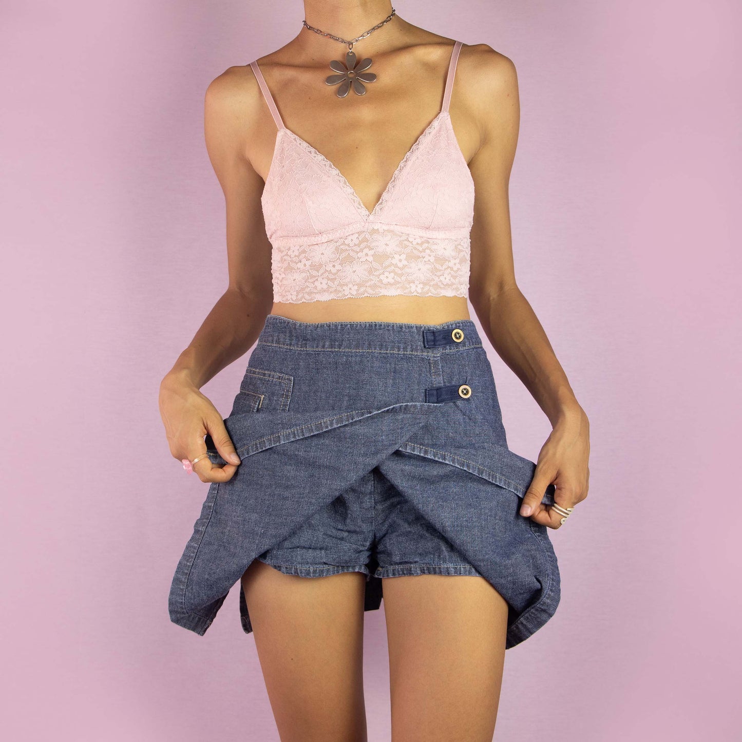 The Y2K Denim Wrap Mini Skirt is a vintage 2000s piece featuring a mid-rise fit and a unique wrap-style design with built-in shorts underneath. Made from medium-wash denim, the skirt has an asymmetrical front with button detailing and a side pocket. Ideal for casual wear and summer outings.