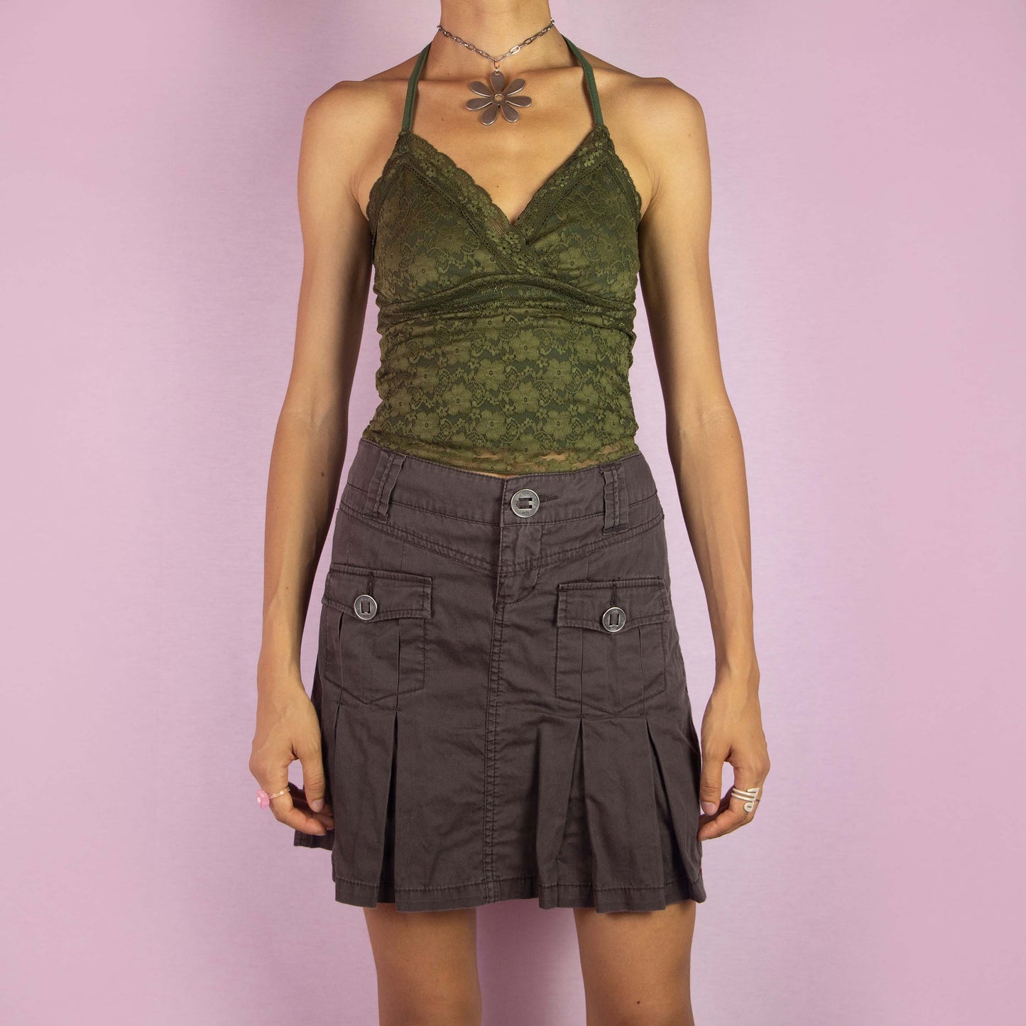 The Y2K Brown Pleated Mini Skirt is a vintage 2000s piece featuring a mid-rise fit, pleated details along the front, and buttoned pockets. Made from cotton, it has a single-button and zipper closure. Ideal for everyday wear or summer outings.