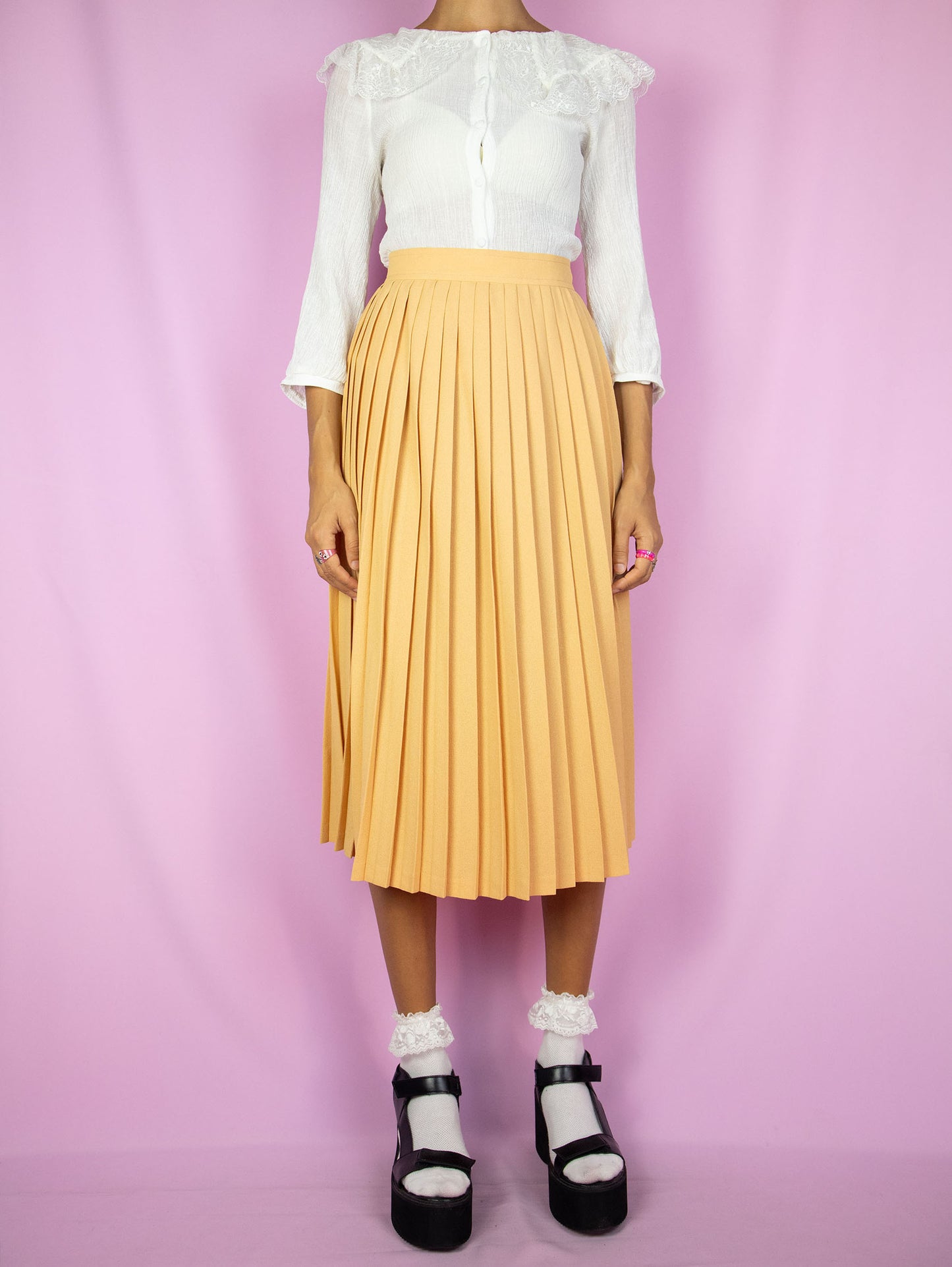 The Vintage 80s Orange Pleated Midi Skirt is a pastel light orange skirt with a back zipper closure. Classic preppy 1980s skirt.