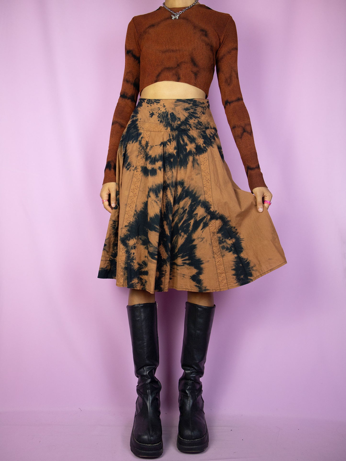 The Vintage 90s Tie Dye Midi Skirt is a statement piece featuring a tie-dye pattern in brown and black, a high-waisted fit with eyelet details and a side zipper closure. Perfect for festival wear or summer outings.