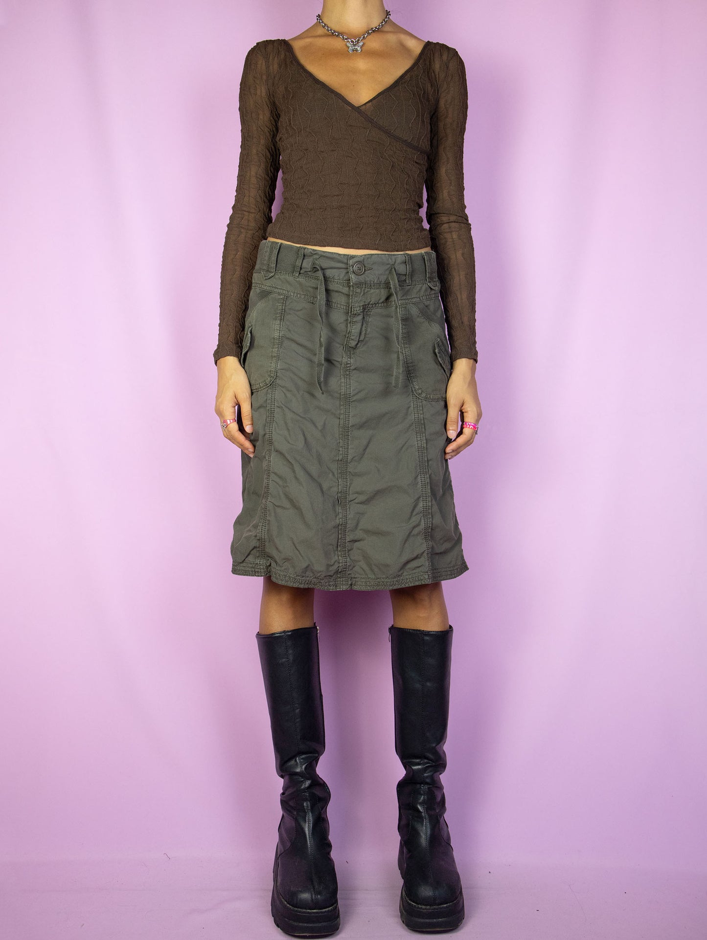 The Y2K Subversive Khaki Cargo Skirt is a vintage dark khaki green flared skirt with pockets and a front zipper closure. A gorgeous utility cargo style gorpcore grunge midi skirt from the 2000s.
