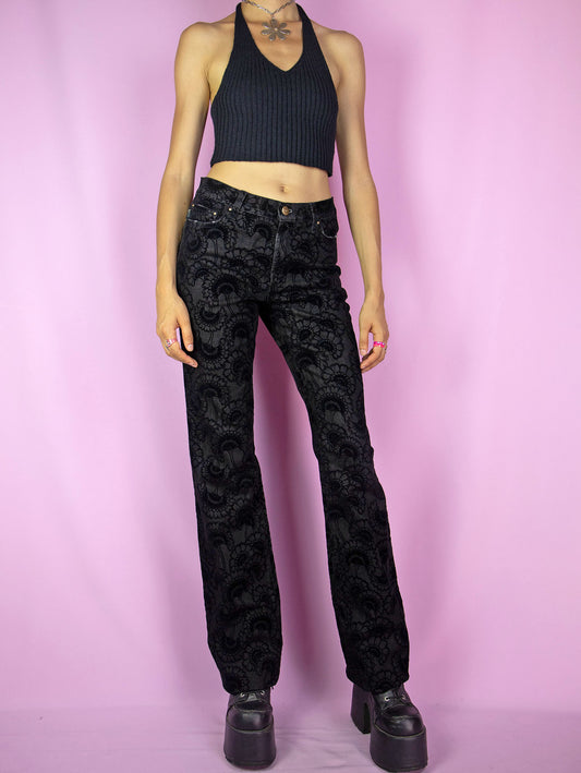 The Vintage Y2K Cavalli Black Jeans are mid-rise black straight-leg pants, offering a subtle stretch and adorned with floral velvet details. These iconic cyber Roberto Cavalli trousers date back to the 2000s.