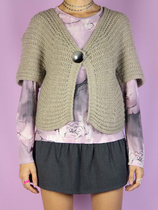 The Y2K Beige Knit Bolero Shrug is a vintage 2000s boho light brown chunky knit cropped cardigan jacket with short sleeves, a single-button closure, and made of a blend of wool and mohair.