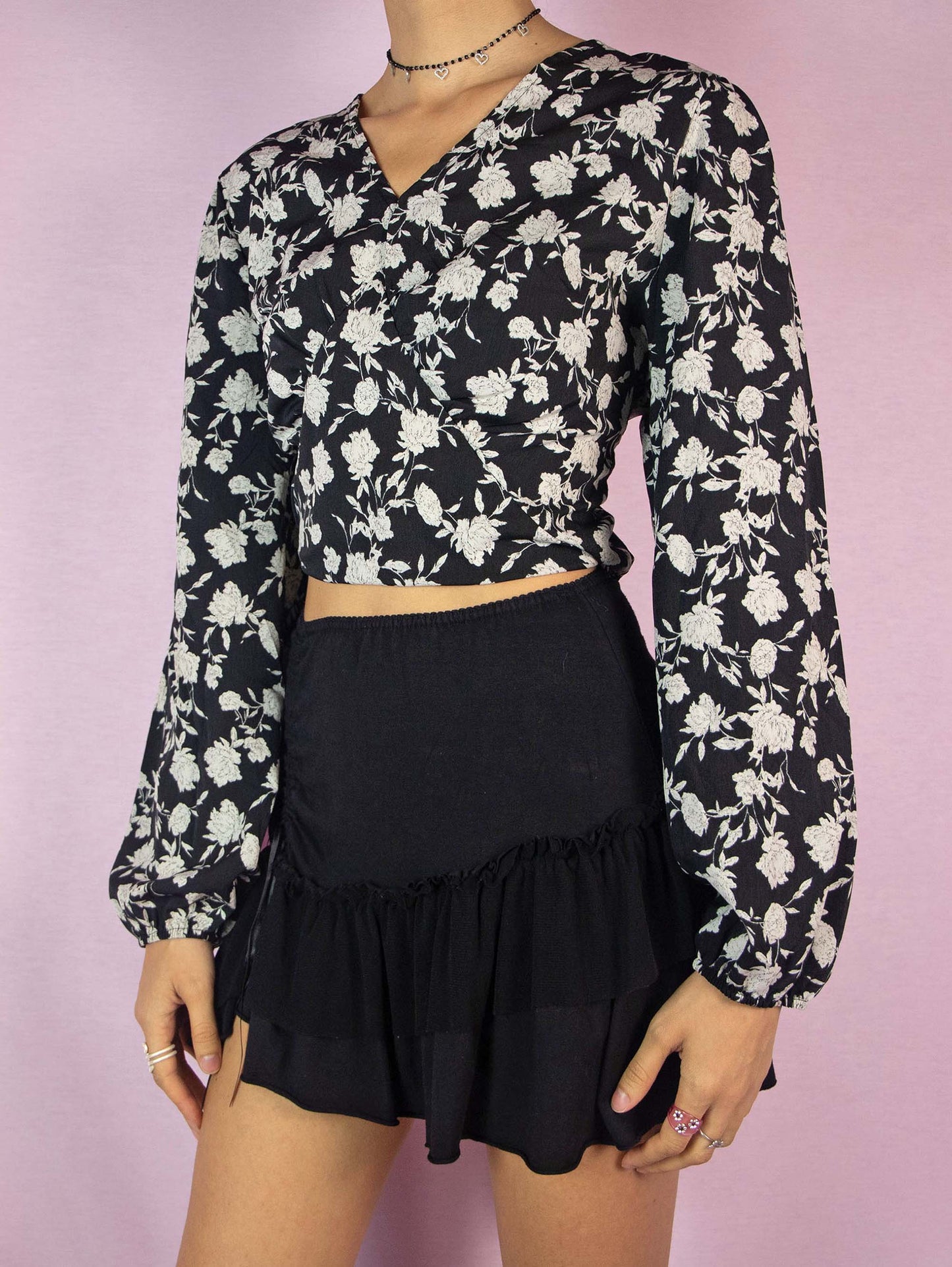 The Y2K Black Floral Tie Back Top is a vintage 2000s boho blouse with a floral graphic print, balloon sleeves, V-neckline, and elastic at the waist.