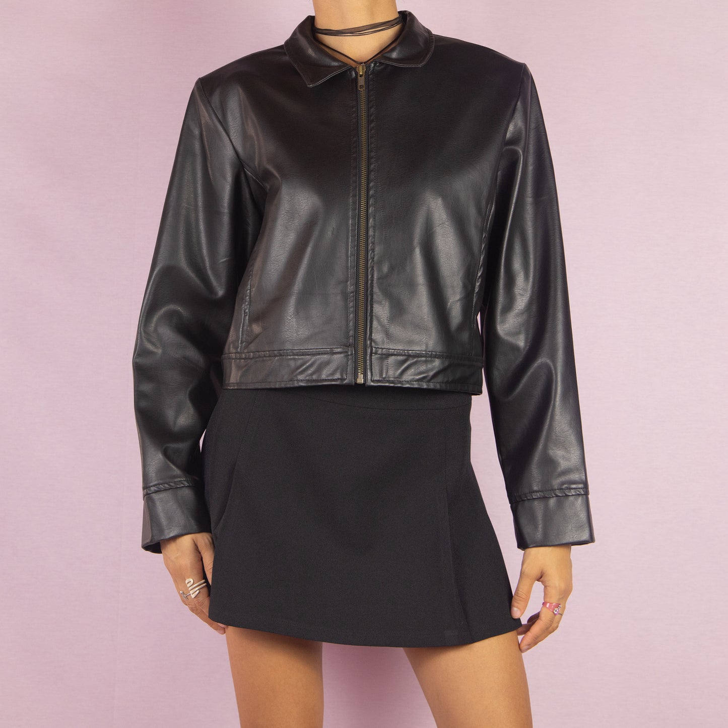 The Y2K Black Faux Leather Jacket is a vintage 2000s sleek and minimalist piece featuring a zip-up front, classic collar, shoulder pads, cropped cut, and a smooth faux leather finish. Ideal for casual fall looks or a night out.