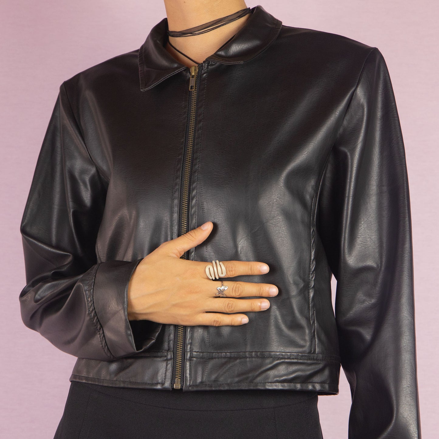 The Y2K Black Faux Leather Jacket is a vintage 2000s sleek and minimalist piece featuring a zip-up front, classic collar, shoulder pads, cropped cut, and a smooth faux leather finish. Ideal for casual fall looks or a night out.