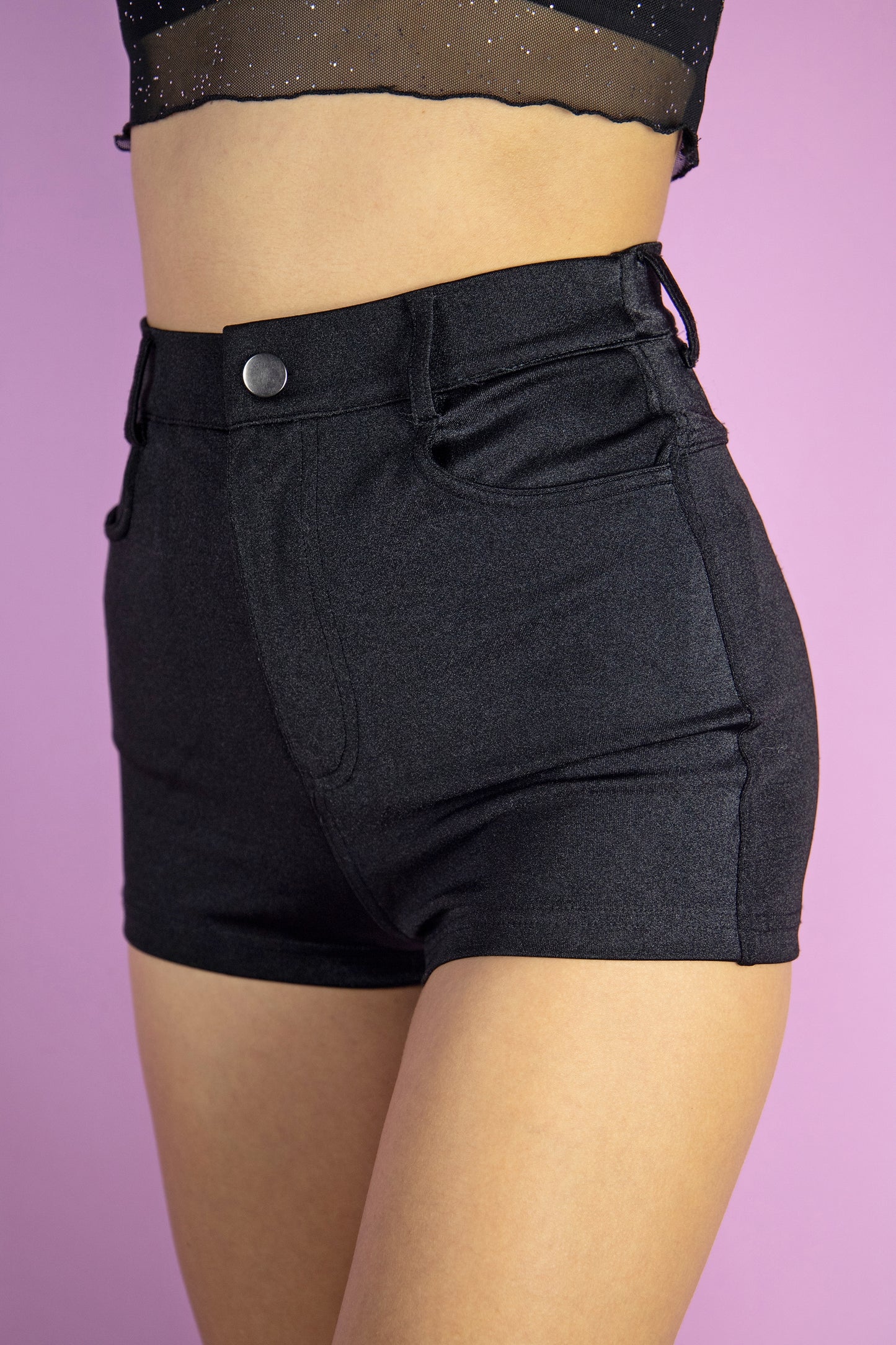 The Y2K Black Booty Shorts are vintage high waisted shiny black stretch shorts with pockets. Cyber party night 2000s shorts.