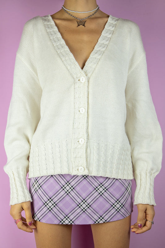 The Vintage 90s White Knit Cardigan is a white cardigan with cable knit details, a v-neck and button closure. Casual preppy style 1990s sweater.