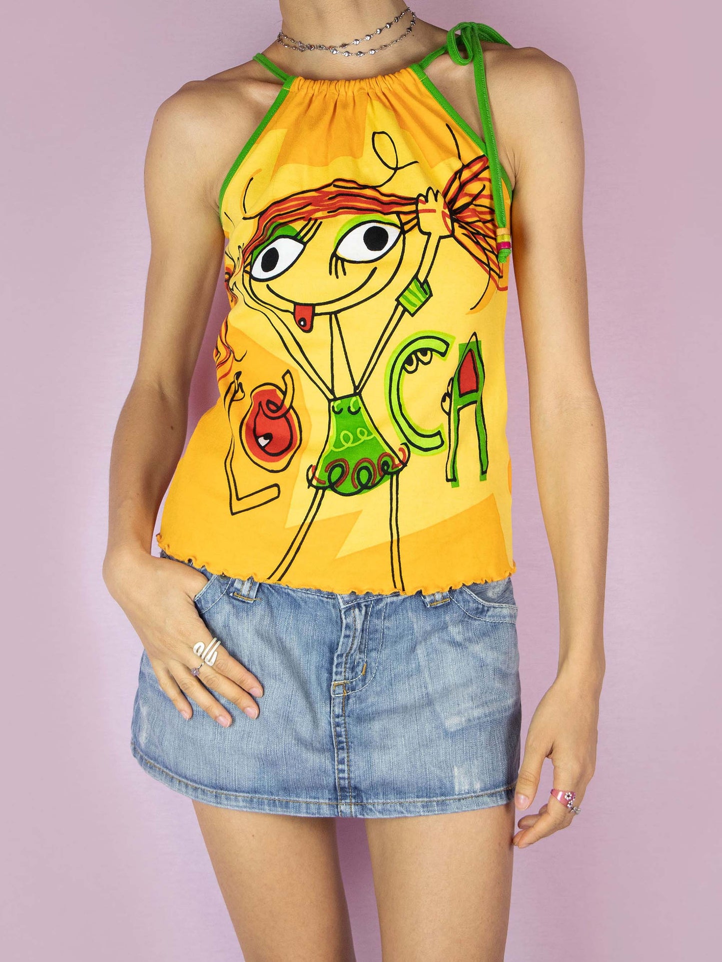 The Y2K Printed Sleeveless Top is a vintage 2000s yellow graphic halter top that features a vibrant cartoon design on the front, showcasing playful and colorful illustrations, making it perfect for a fun, casual summer look.