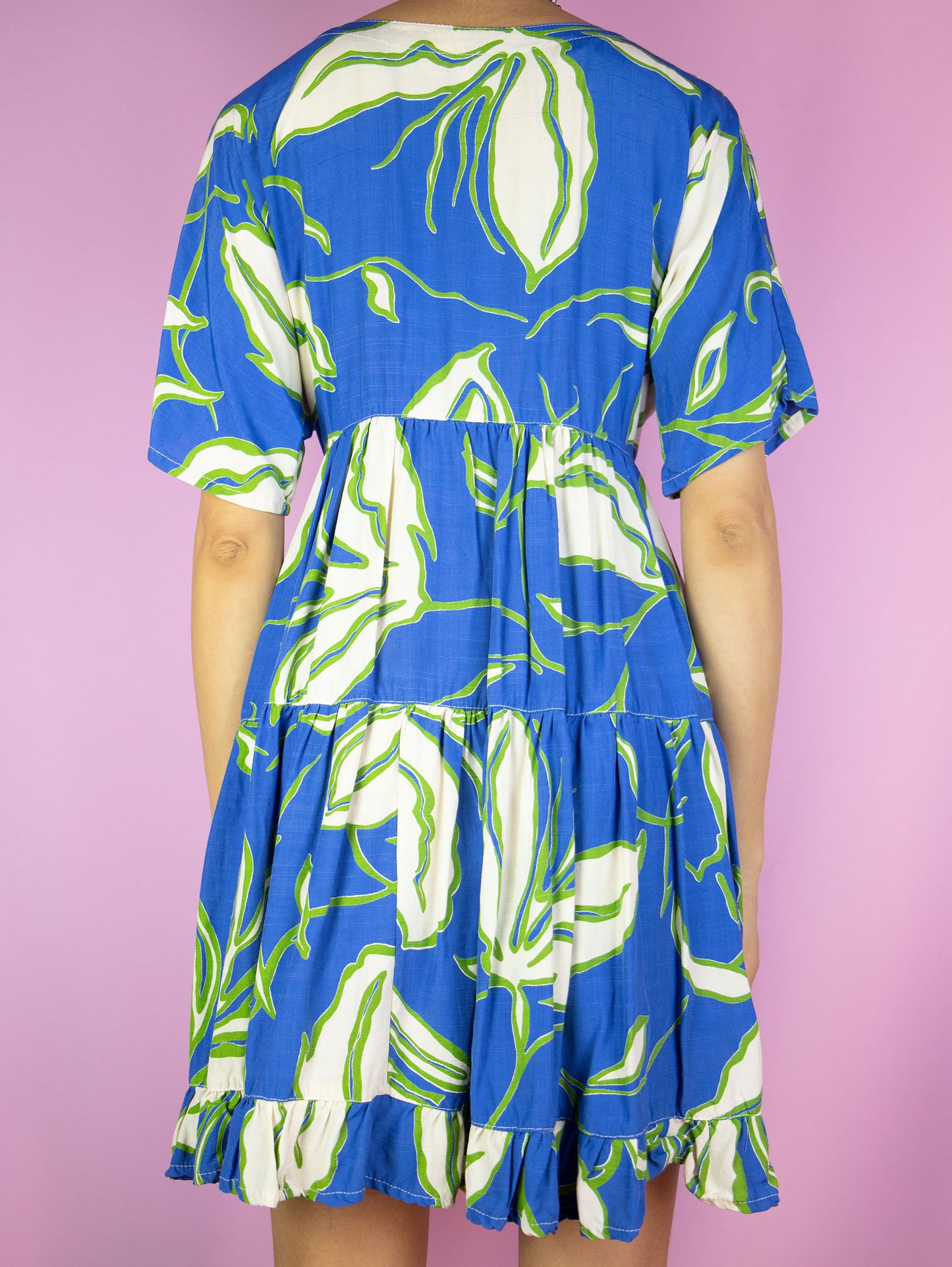 The Vintage 90s Floral Print Mini Dress is a boho summer beach style blue multicolored short sleeve tiered babydoll dress with buttons and a ruffle hem.