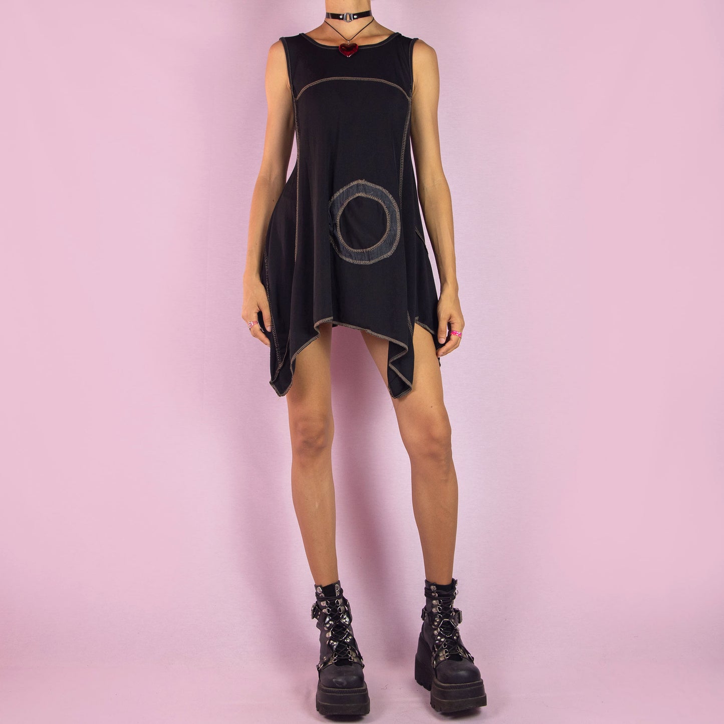 The Y2K Black Asymmetric Sleeveless Top is a vintage 2000s shirt featuring a flowy, oversized silhouette with bold circular stitched detailing. Made from stretchy fabric, this top has an asymmetric hemline, perfect for summer casual wear or layering for a unique, statement look. Made in Italy.