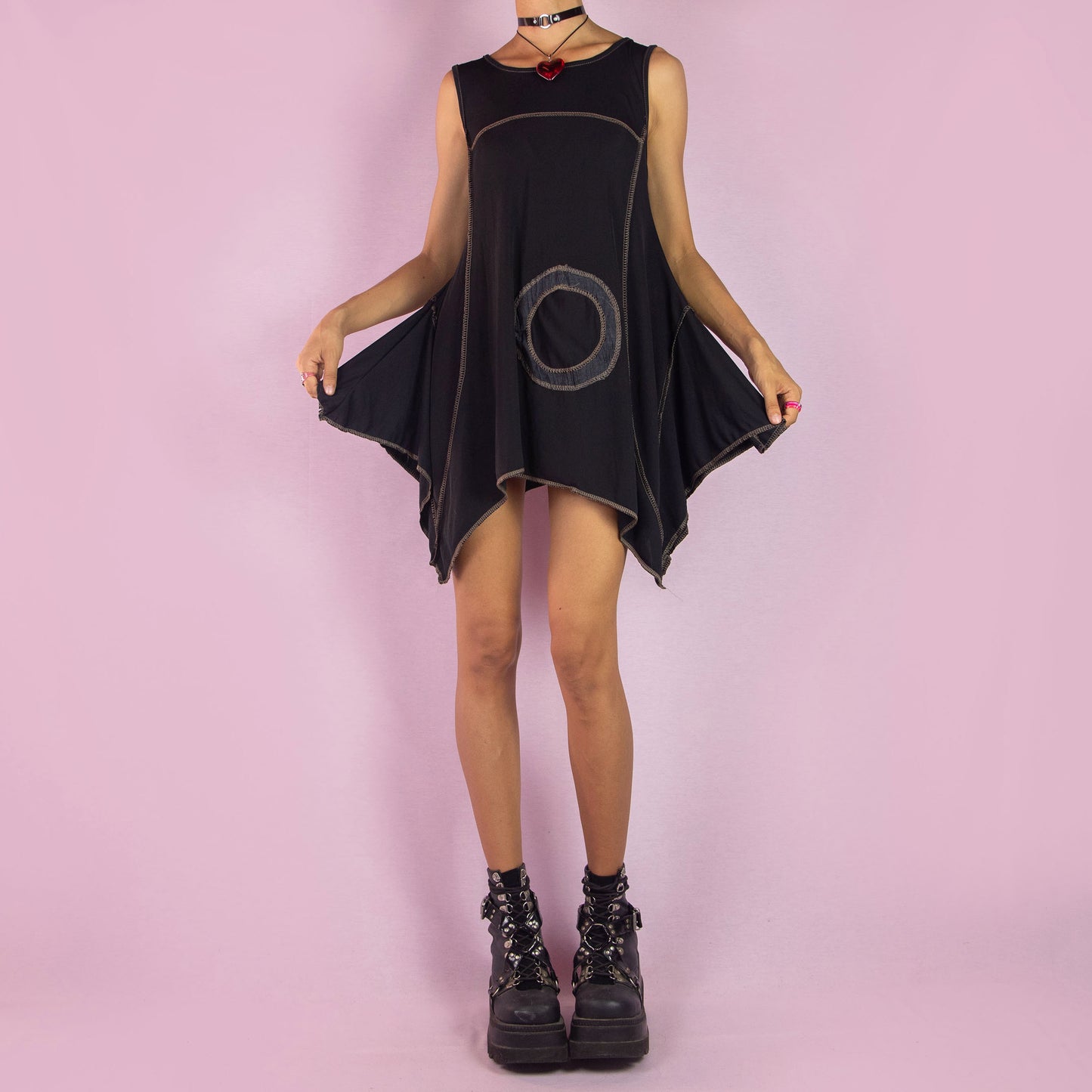 The Y2K Black Asymmetric Sleeveless Top is a vintage 2000s shirt featuring a flowy, oversized silhouette with bold circular stitched detailing. Made from stretchy fabric, this top has an asymmetric hemline, perfect for summer casual wear or layering for a unique, statement look. Made in Italy.