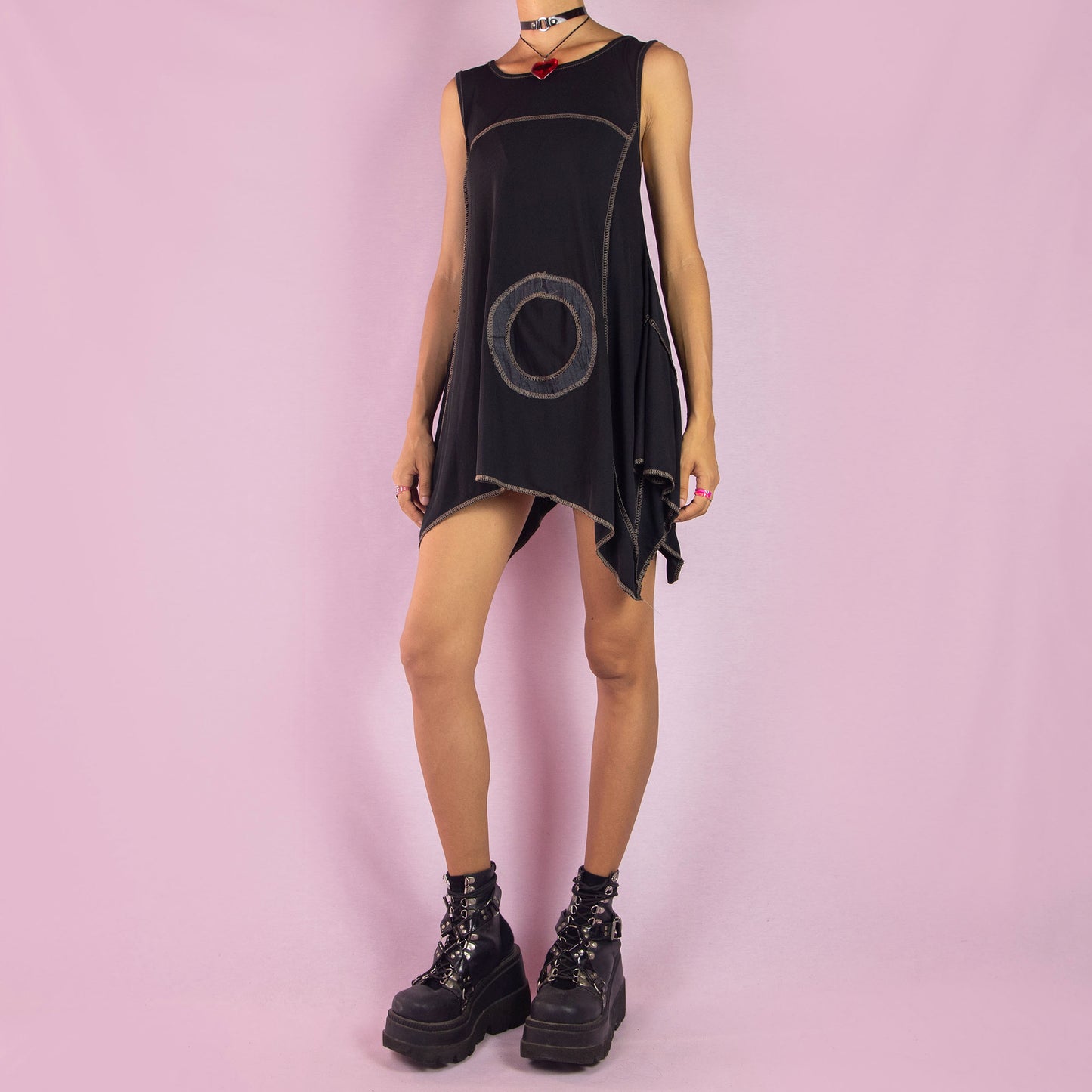 The Y2K Black Asymmetric Sleeveless Top is a vintage 2000s shirt featuring a flowy, oversized silhouette with bold circular stitched detailing. Made from stretchy fabric, this top has an asymmetric hemline, perfect for summer casual wear or layering for a unique, statement look. Made in Italy.