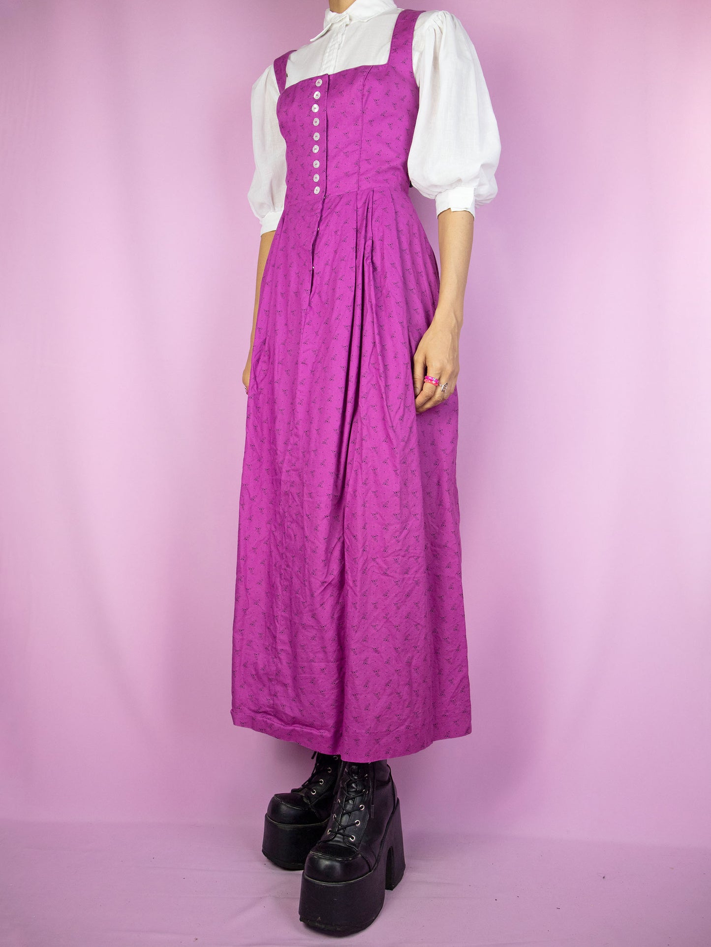 The Vintage 90s Purple Prairie Maxi Dress is a sleeveless floral dress with pleats and buttons. Boho country western cottage inspired 1990s midi dress. The white blouse shown underneath is not included.