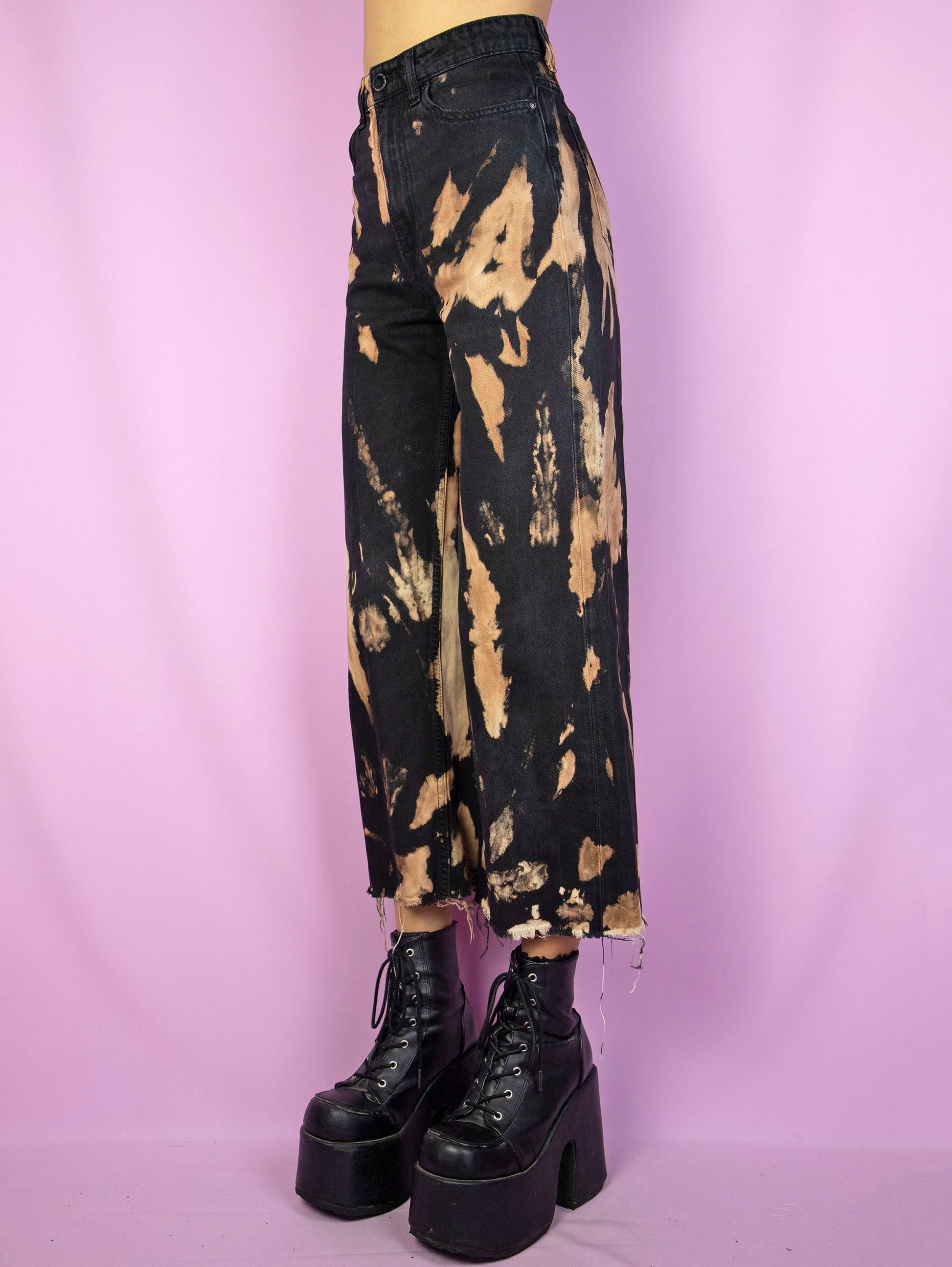 The Y2K Black Tie Dye Jeans are a vintage high waisted black bleached tie dye capri pants with a frayed hem. Cyber goth 2000s wide leg trousers.