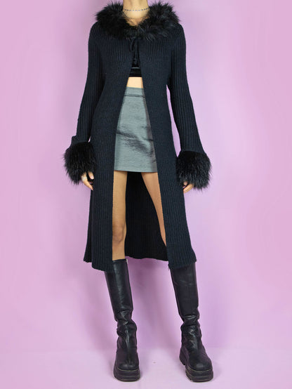 The Y2K Black Knit Duster Jacket is a vintage long black ribbed knit jacket that ties at the front and has faux fur collar and cuffs. Cyber whimsygoth 2000s penny lane style cardigan.