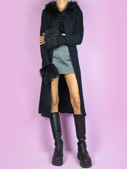 The Y2K Black Knit Duster Jacket is a vintage long black ribbed knit jacket that ties at the front and has faux fur collar and cuffs. Cyber whimsygoth 2000s penny lane style cardigan.