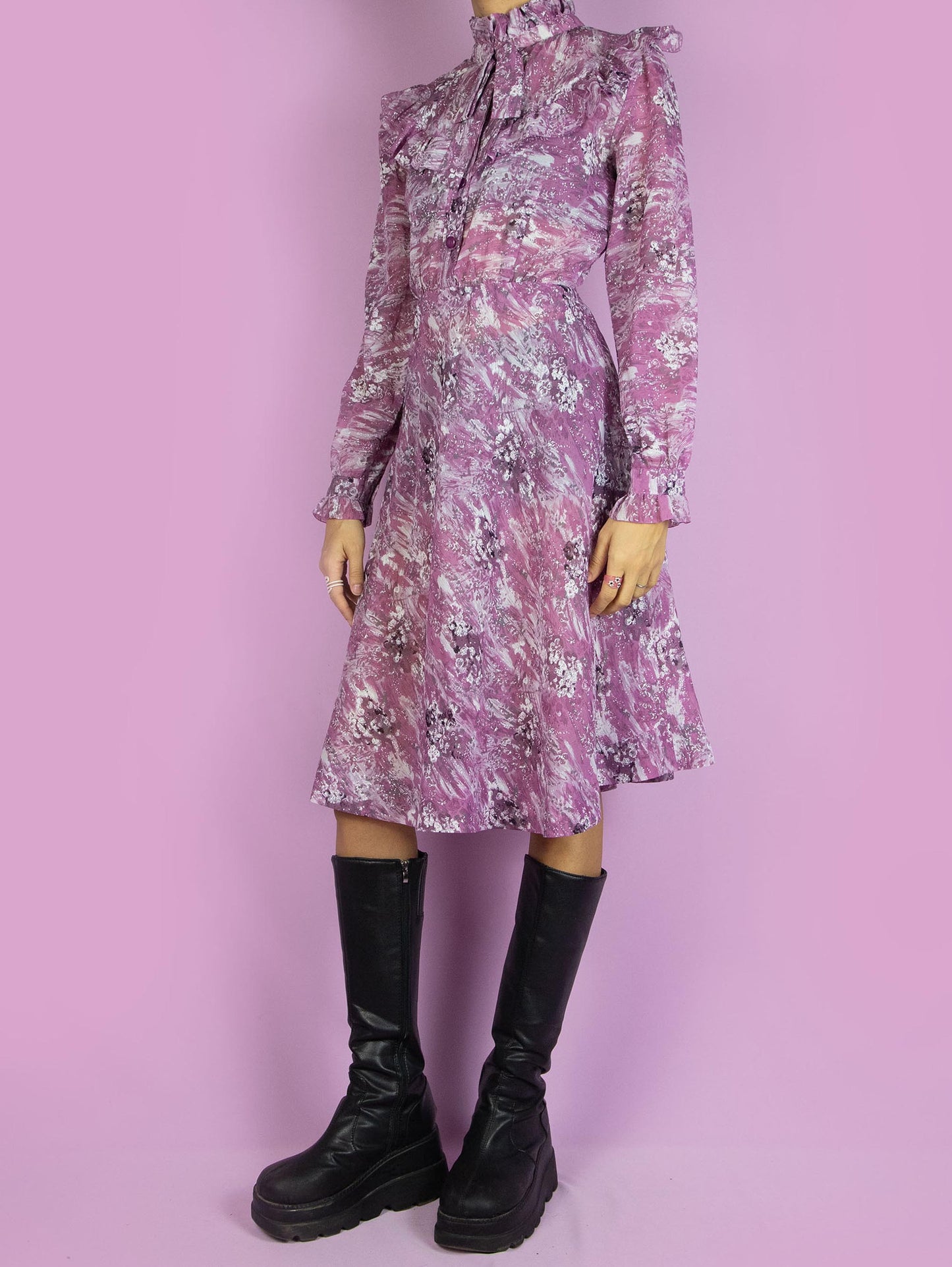 The Vintage 90s Purple Ruffle Collar Dress is a semi-sheer abstract purple dress with long sleeves, buttons, ruffles, and a bow at the collar. Boho retro 1990s romantic midi dress.