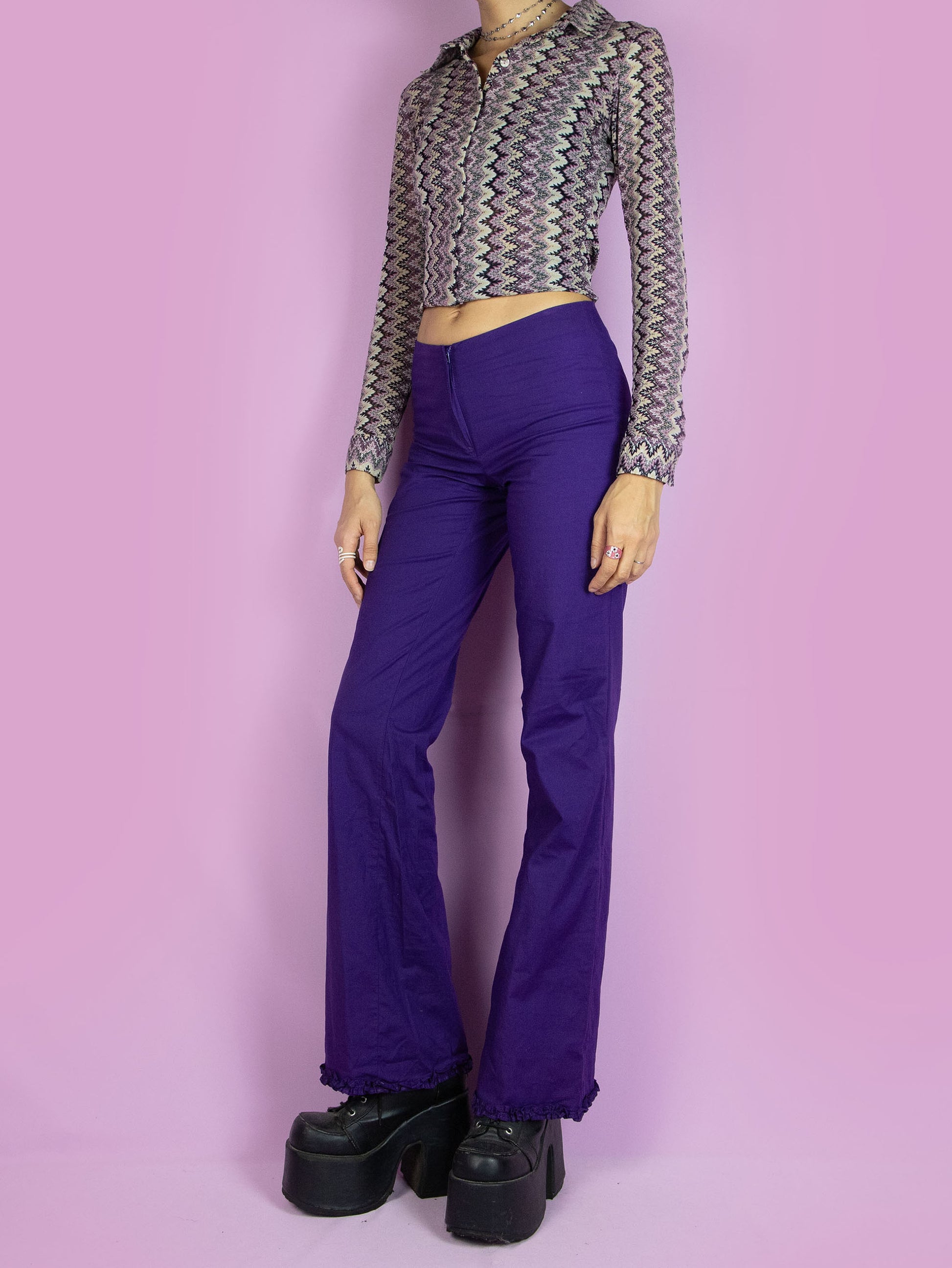 The Vintage 90s Dark Purple Flare Pants are mid-rise purple pants, slightly elastic and flared, with a front zipper closure and a gathered ruffle detail at the hem. Boho retro 1990s trousers.