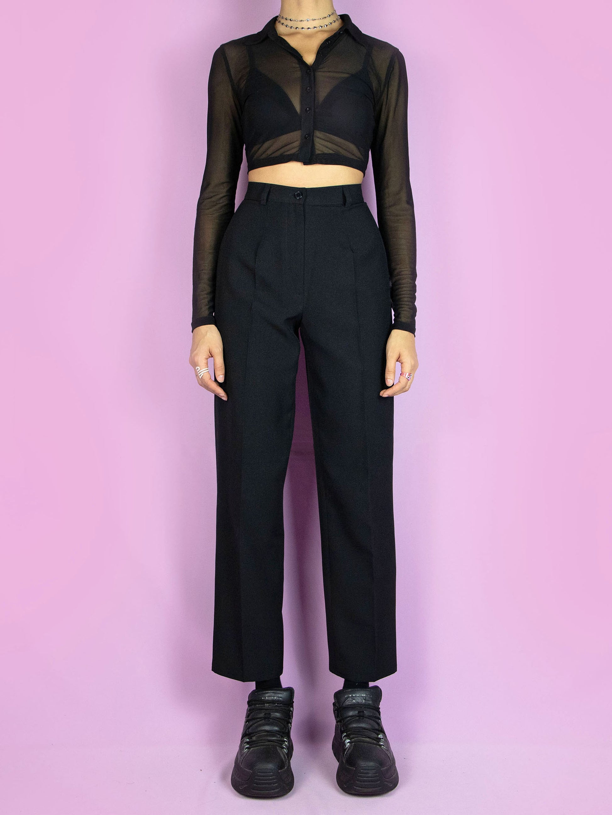 The Vintage 90s Black Pleated Trousers are high-waisted black pants with pleats and a front zipper closure. Elegant classic tailored 1990s office pleated tapered trousers.