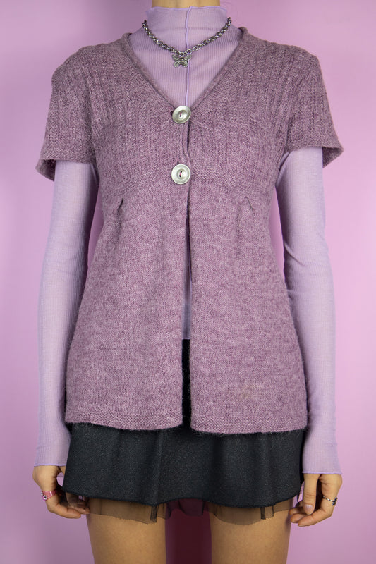 The Vintage Y2K Purple Short Sleeve Cardigan is a flared, short-sleeved knit cardigan in a lovely shade of purple, featuring a two-button closure. This charming piece represents the super cute fairy grunge style of the 2000s.