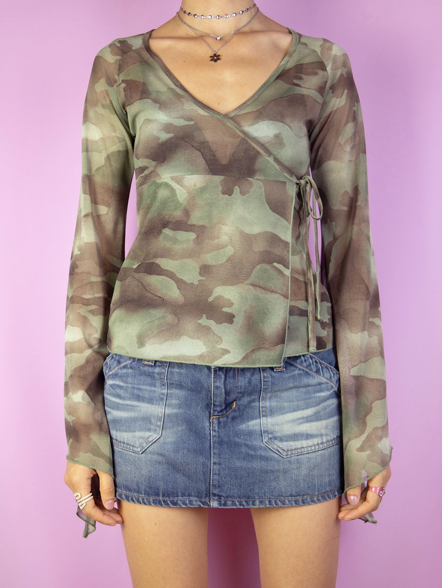 The Y2K Camouflage Mesh Top is a vintage green and brown camo print semi-sheer mesh wrap top with side tie detail and bell sleeves. Cyber grunge 2000s graphic shirt.