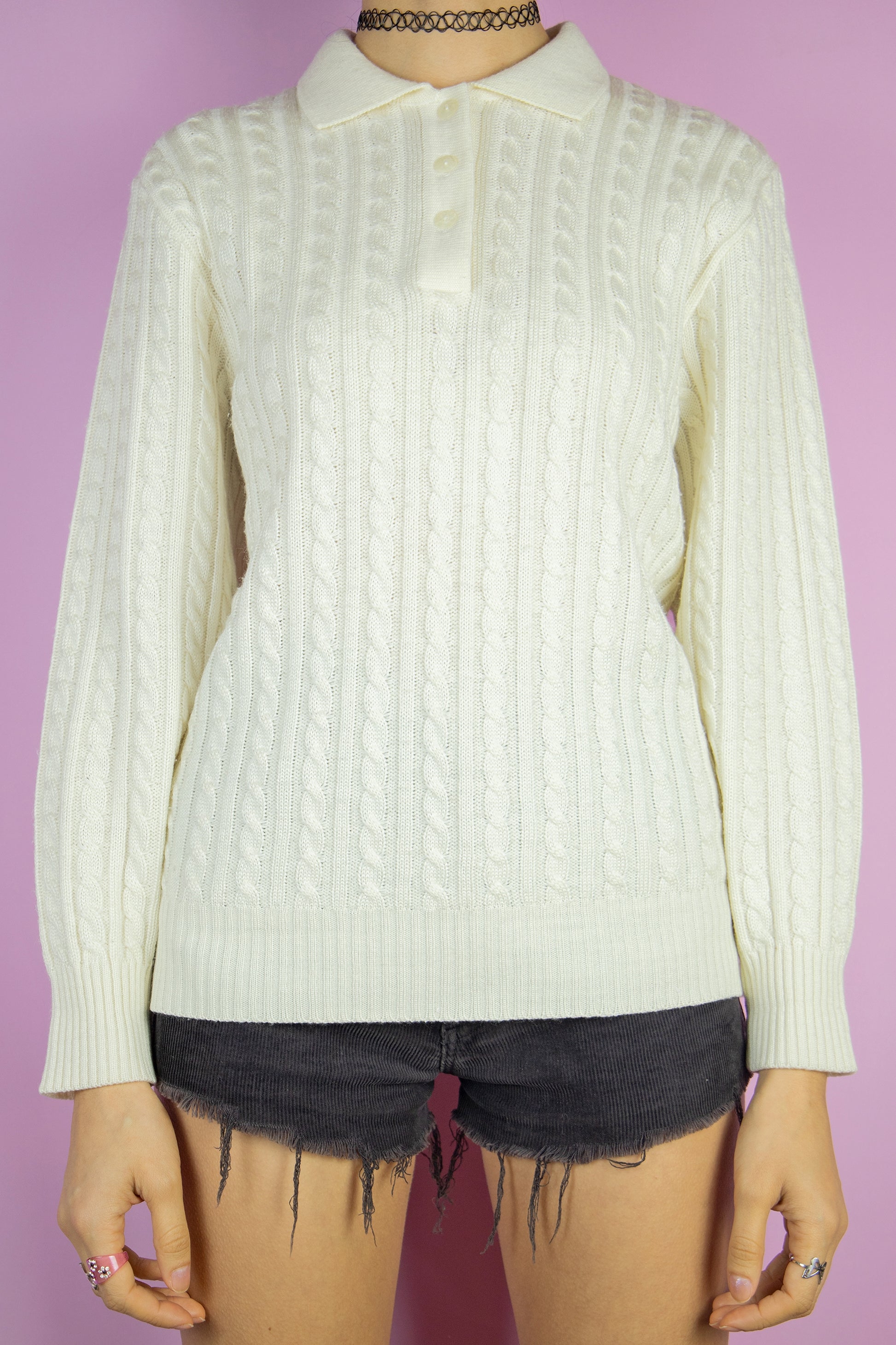 The Vintage 90's White Cable Knit Sweater is a cream white cable knit jumper featuring a collar and three buttons. This classic vintage retro half-button pullover captures the style of the 1990s.