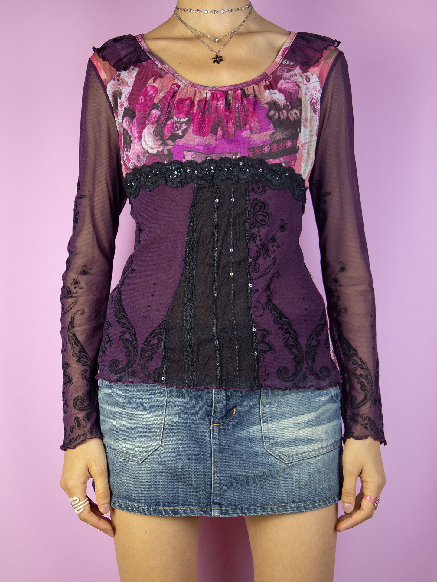The Y2K Graphic Purple Mesh Top is a vintage dark purple and pink abstract floral semi-sheer mesh long-sleeve top with ruffles, black lace detailing, and lettuce hem. Cyber fairy grunge 2000s shirt.
