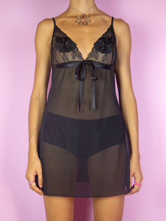 The Y2K Black Mesh Slip Dress is a vintage black semi-sheer mesh cami mini dress with embroidered flowers, adjustable straps and a bow on the front. Romantic sexy 2000s lingerie night dress.