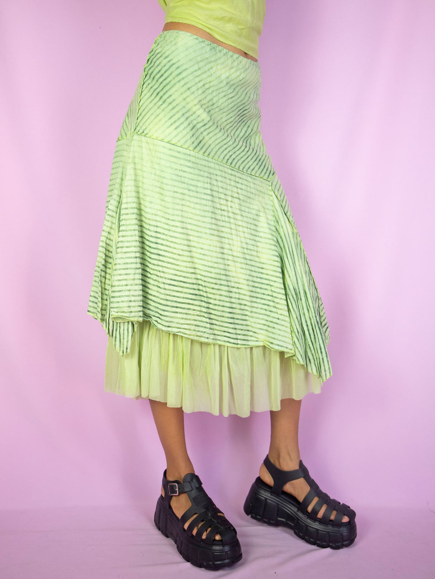 The Y2K Green Asymmetric Midi Skirt is a vintage green striped skirt with pointed asymmetric layers, semi-sheer mesh hem and elastic waist. Cyber fairy grunge 2000s boho pixie midi skirt.