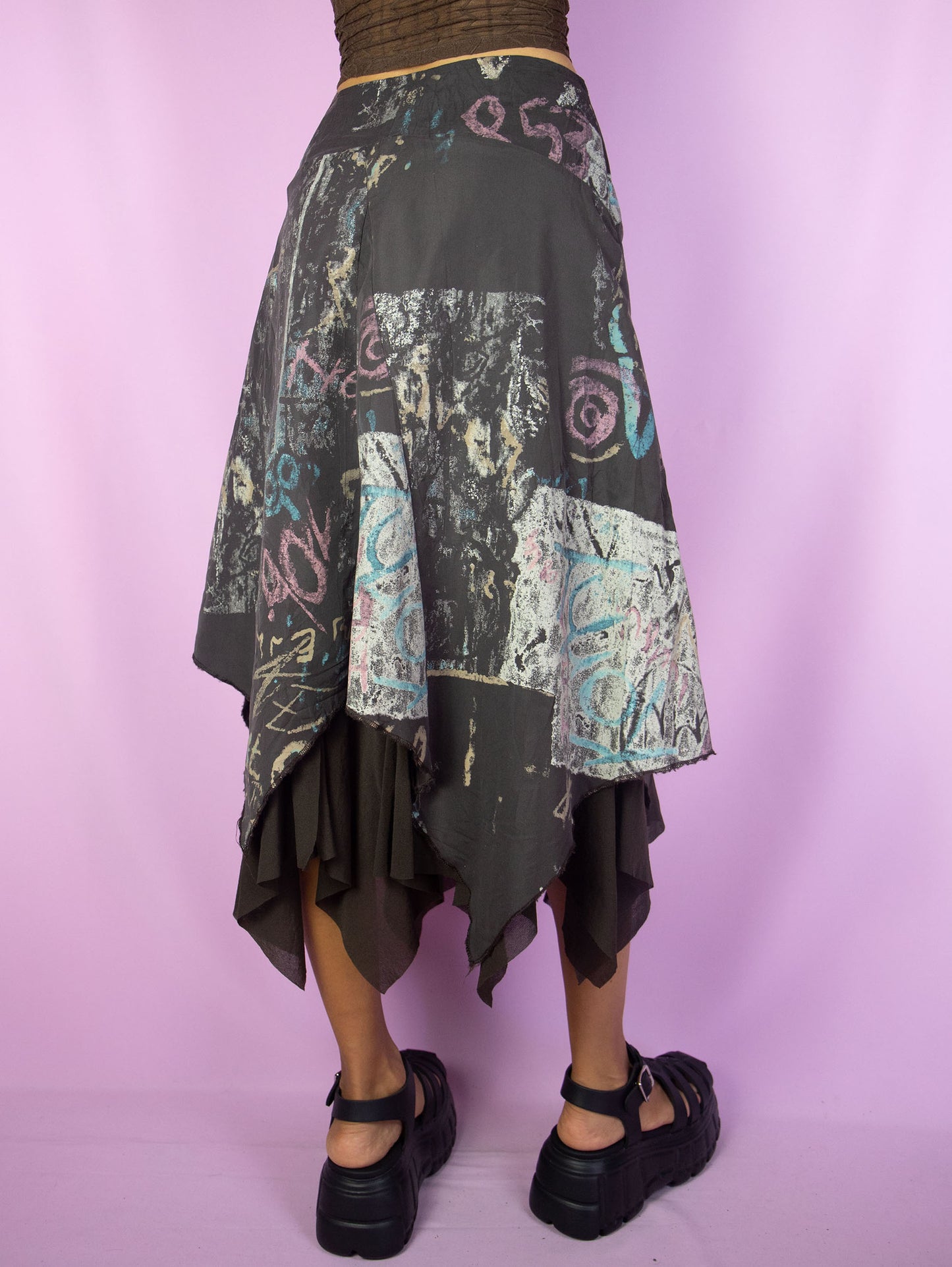 The Y2K Layered Asymmetric Midi Skirt is a vintage 2000s cyber subversive party style dark brown abstract printed skirt with a pointed asymmetrical semi-sheer mesh hem and side zipper closure. Made in France.