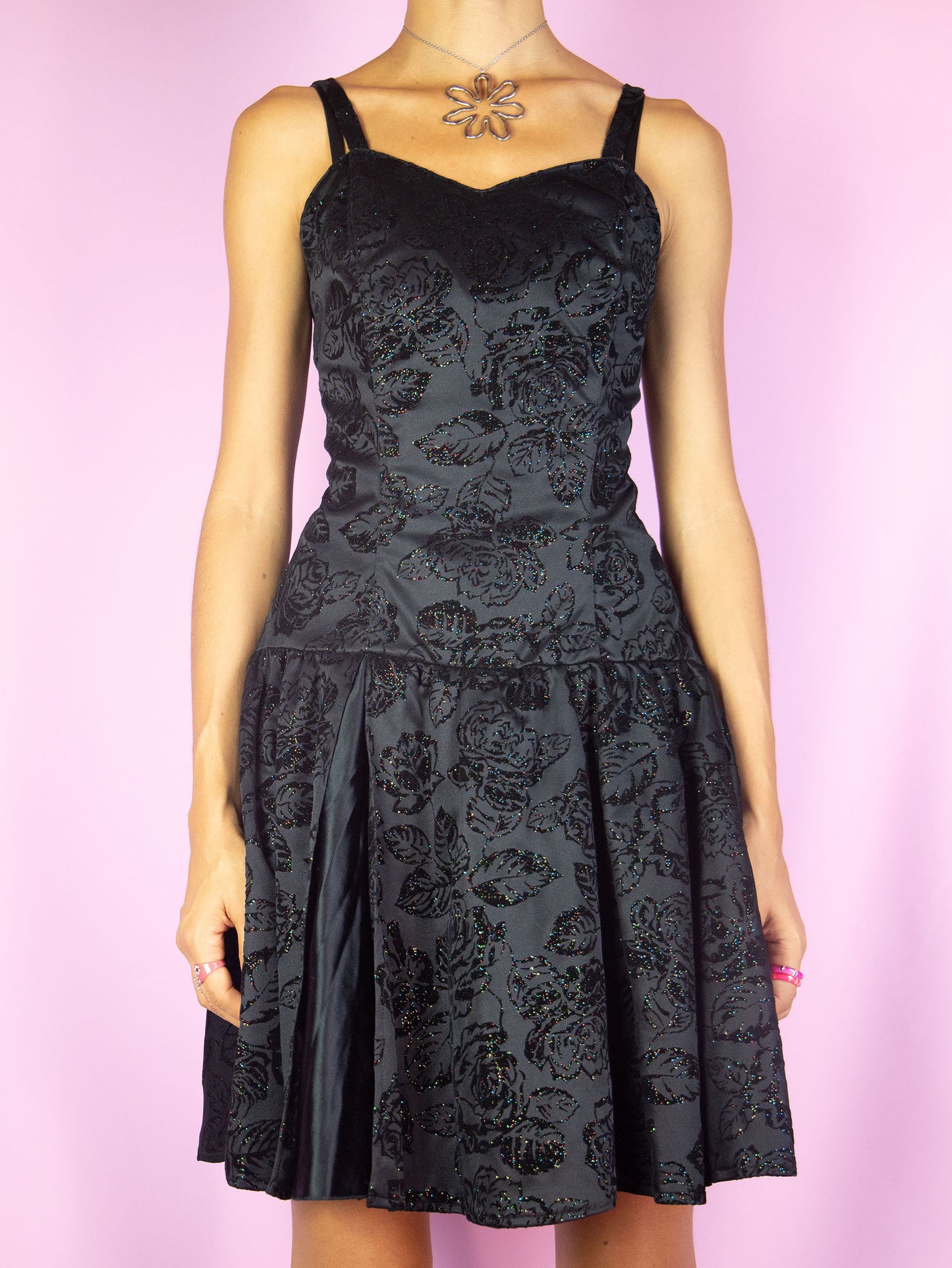 The Vintage 90s Black Party Mini Dress is a sleeveless black dress with a shirred back with a zipper closure and velvet rose floral details and muticolor sparkly glitter. Whimsygoth 1990s night dress.