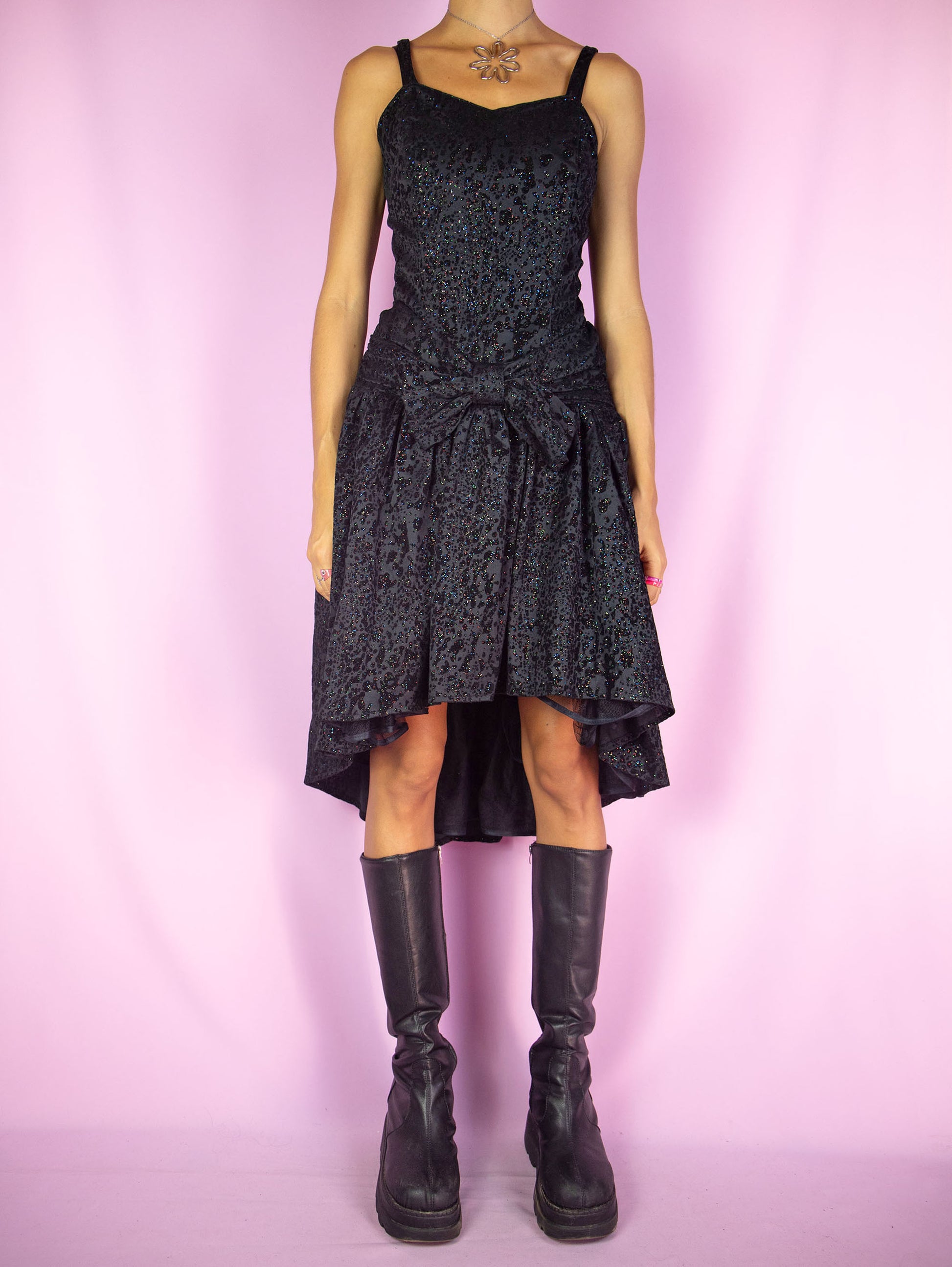 The Vintage 90s Party Black Mini Dress is an asymmetrical black dress with a shirred back, bow on the front, tulle hem and velvet and multicolored shiny glitter details. Whimsygoth 1990s midi dress.