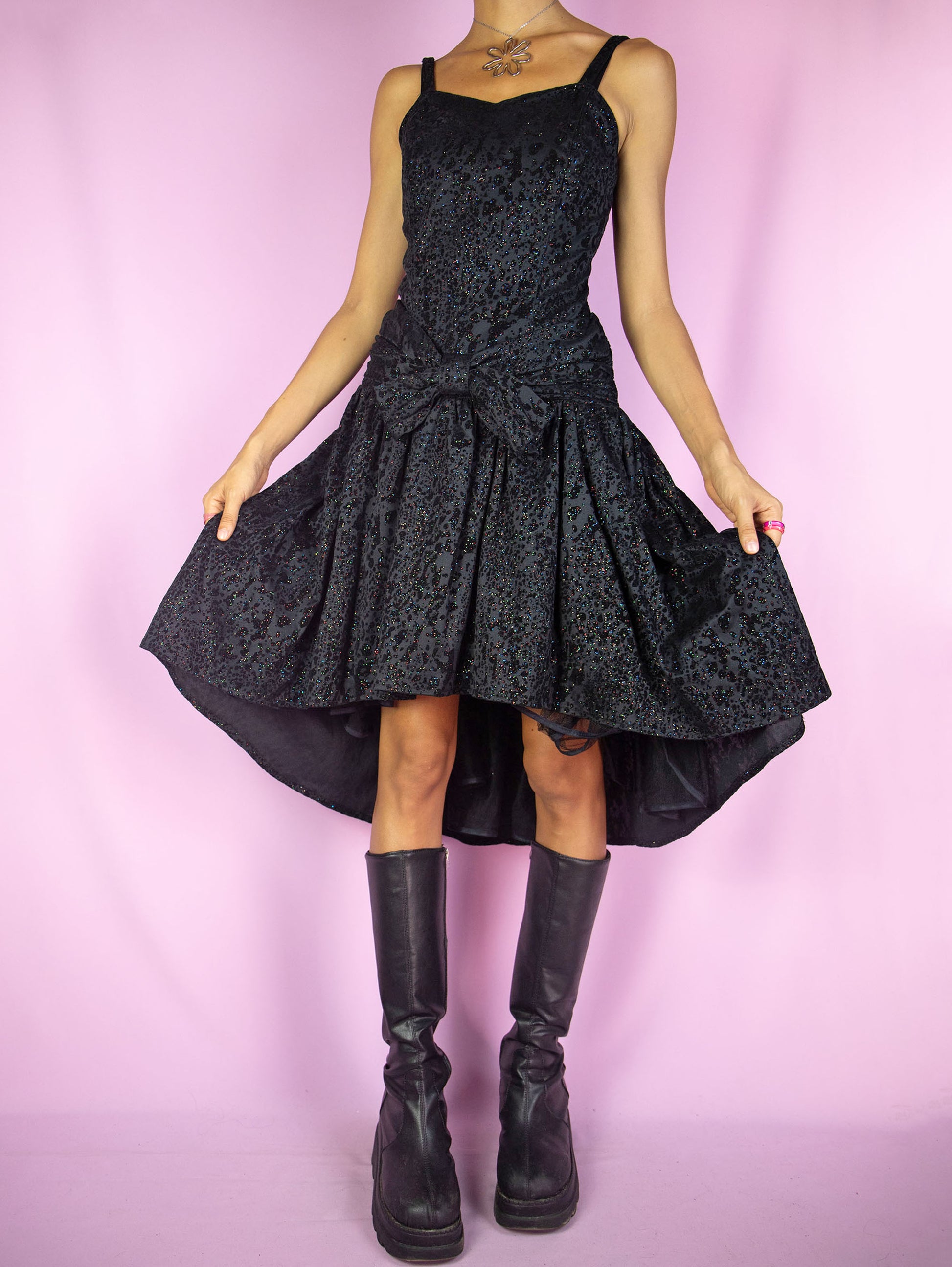The Vintage 90s Party Black Mini Dress is an asymmetrical black dress with a shirred back, bow on the front, tulle hem and velvet and multicolored shiny glitter details. Whimsygoth 1990s midi dress.