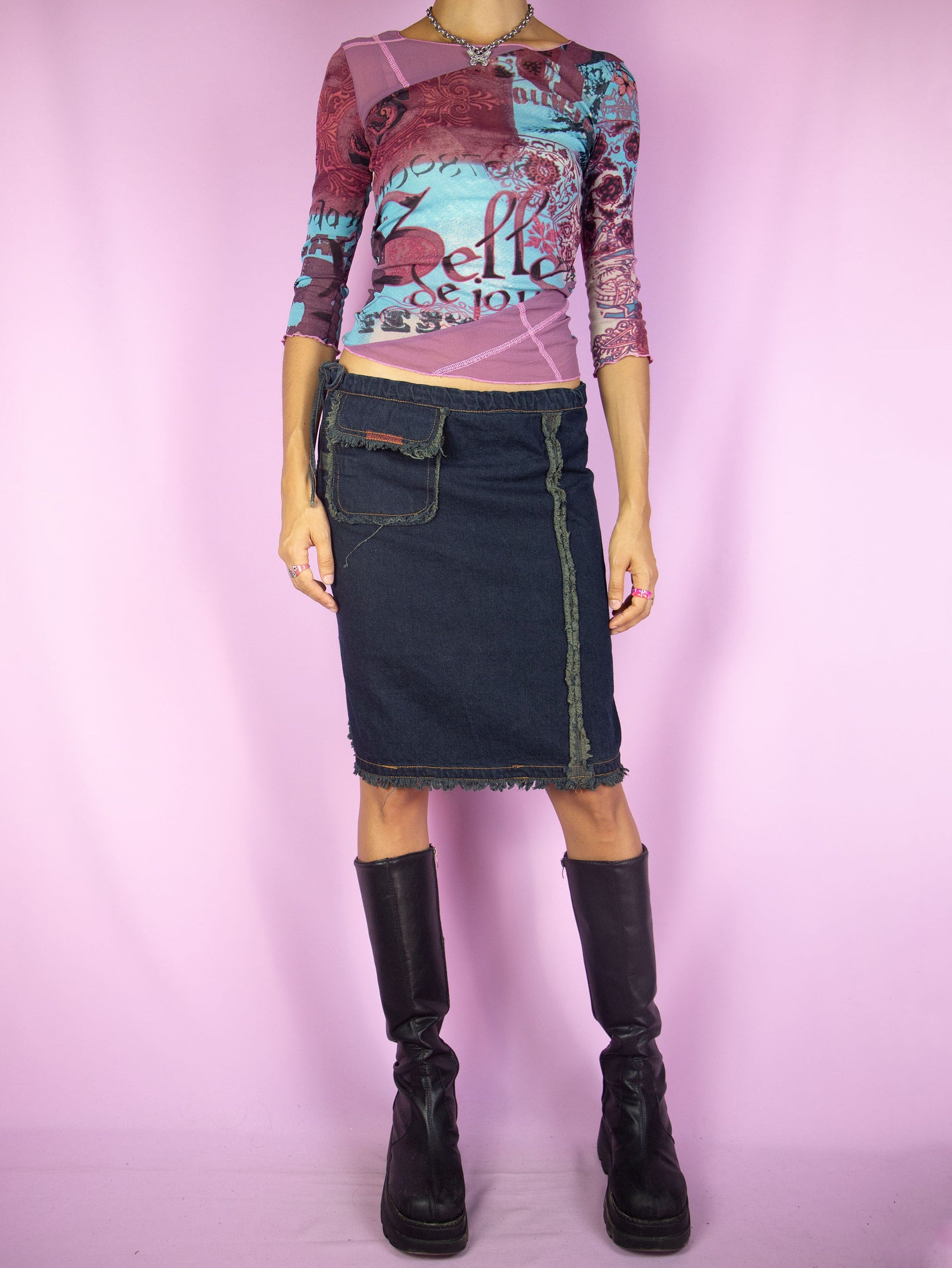 The Y2K Asymmetric Denim Mini Skirt is a vintage dark denim navy blue skirt tied at the side with a pocket and frayed seam details. Cyber goth grunge 2000s subversive gorpcore jean skirt.