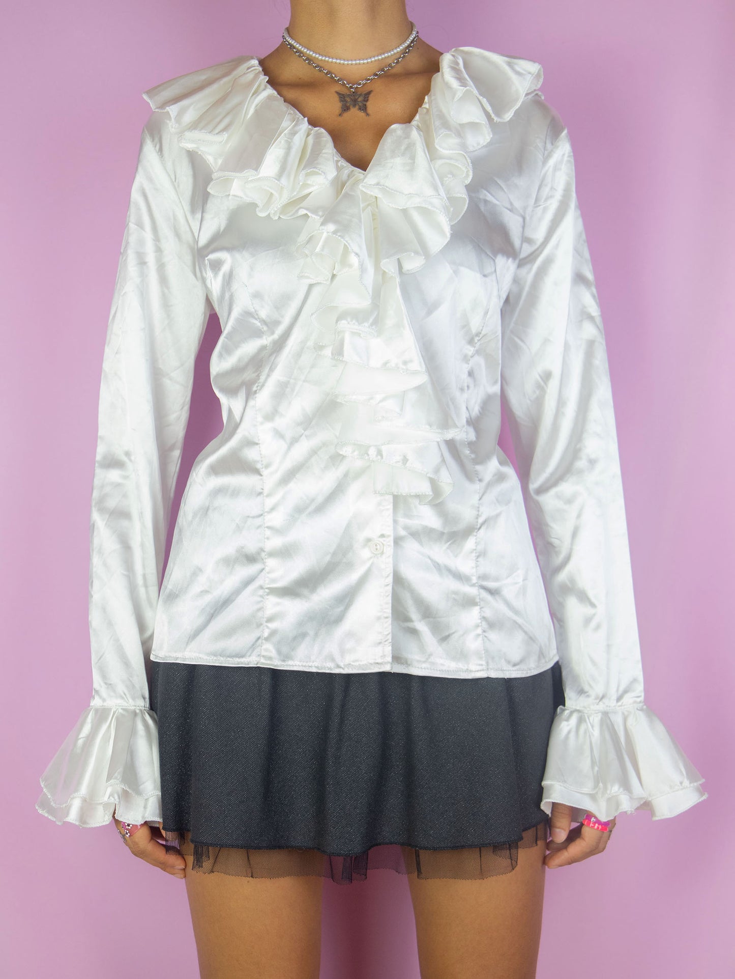 The Vintage 90s White Satin Ruffle Blouse is a shiny satin-style top with a ruffled collar, buttons, and bell sleeves. Romantic elegant 1990s evening party shirt.