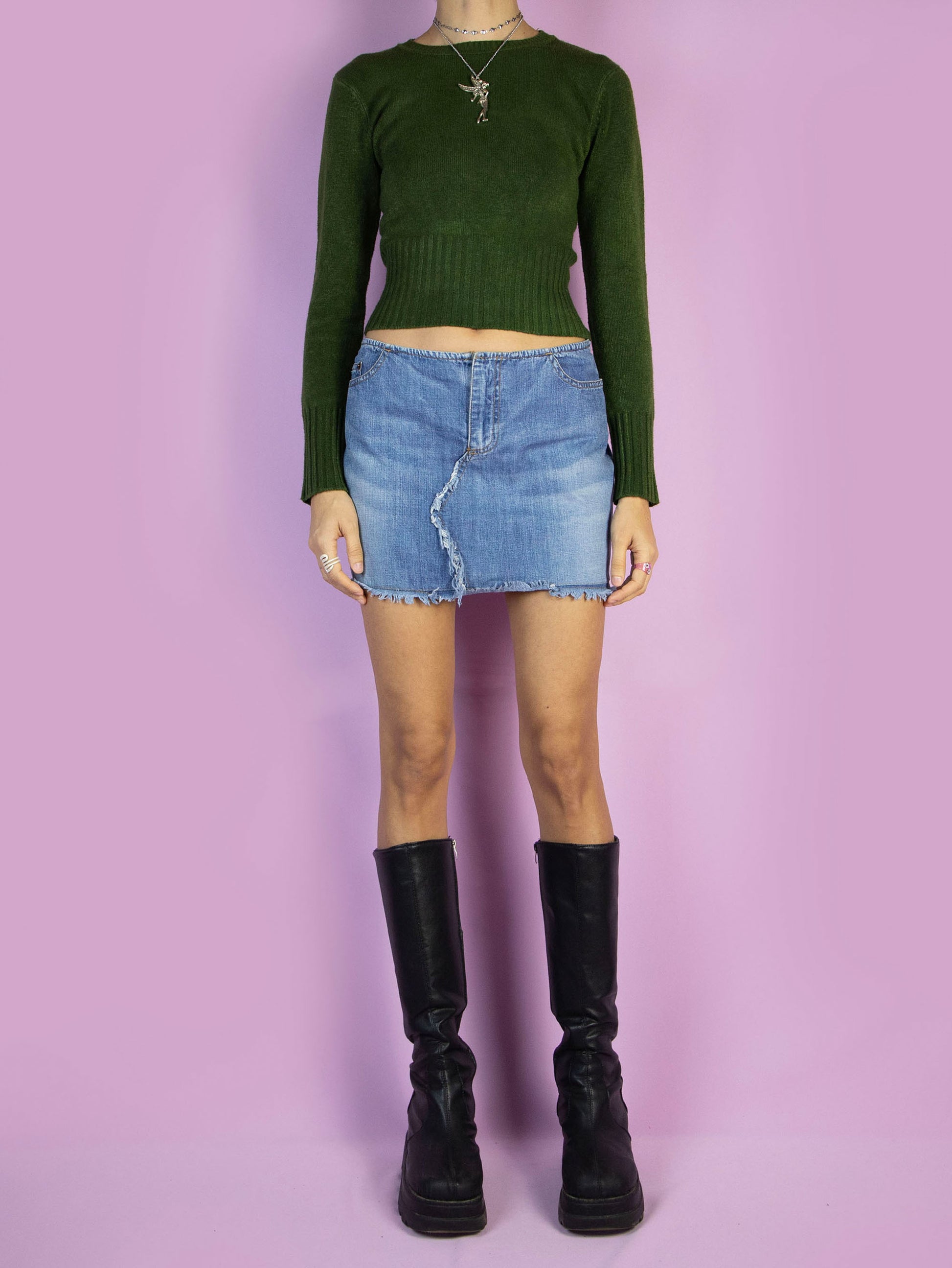 The Y2K Low Waisted Denim Mini Skirt is a vintage 2000s cyber grunge style low-rise jean mini skirt with pockets, a front zipper closure, and frayed details.