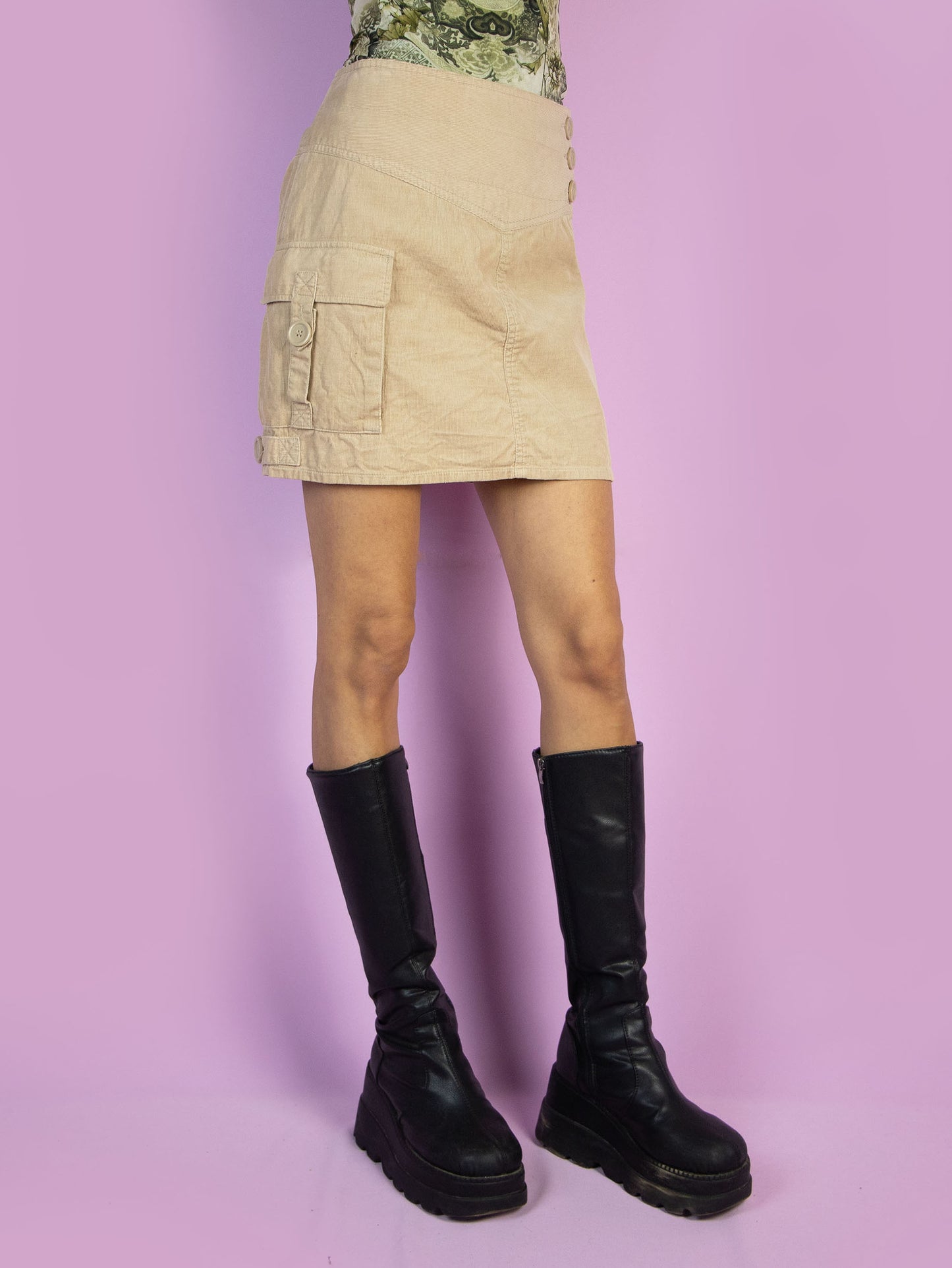 The Y2K Grunge Beige Mini Skirt is a vintage beige corduroy skirt with a pocket and a back zipper closure. Subversive utility cargo style 2000s mini skirt.