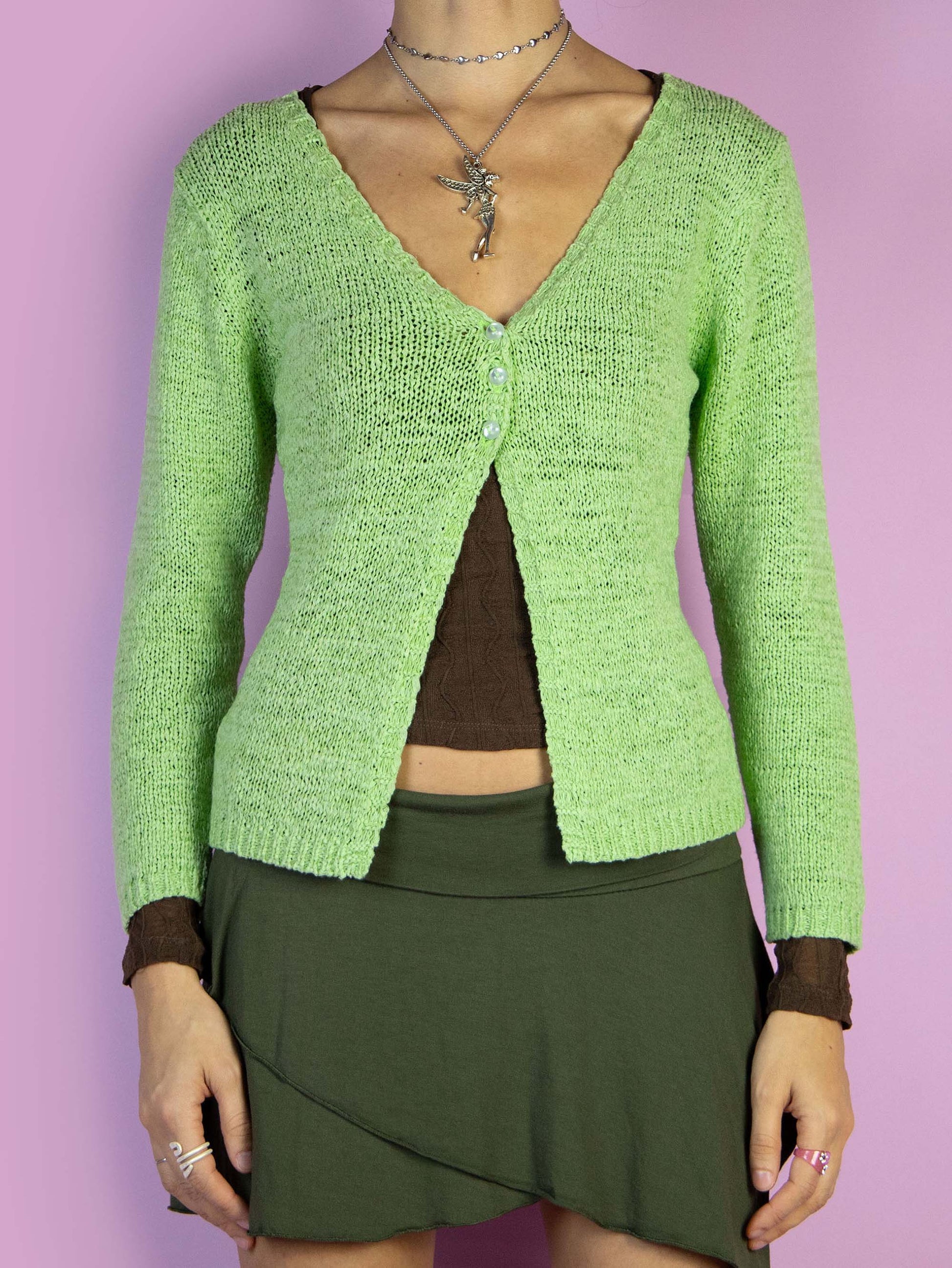 The Y2K Green Three Button Cardigan is a vintage green cardigan with a front slit, V-neck, three-quarter sleeves, and a closure with three buttons. Cyber fairy grunge 2000s knitted sweater.