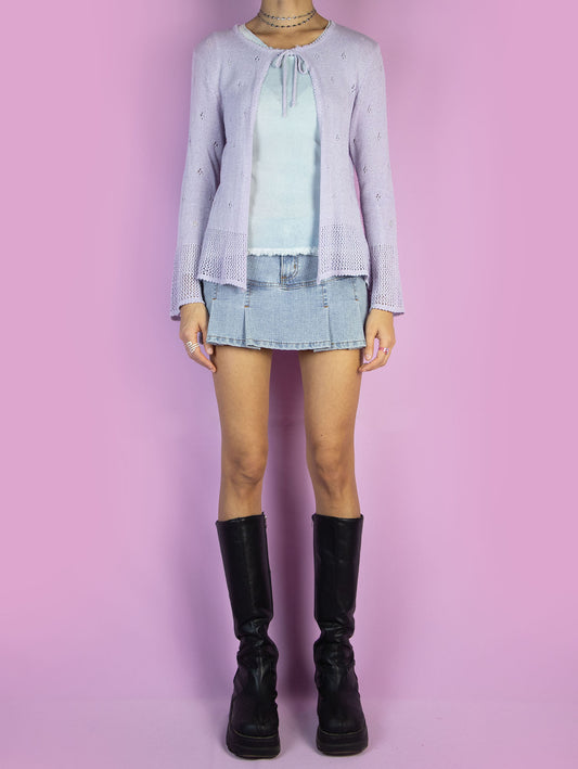 The Y2K Lilac Tie Front Cardigan is a light pastel purple cardigan that ties at the front and features bell sleeves. Cyber fairy grunge 2000s coquette crochet knit bolero jacket.