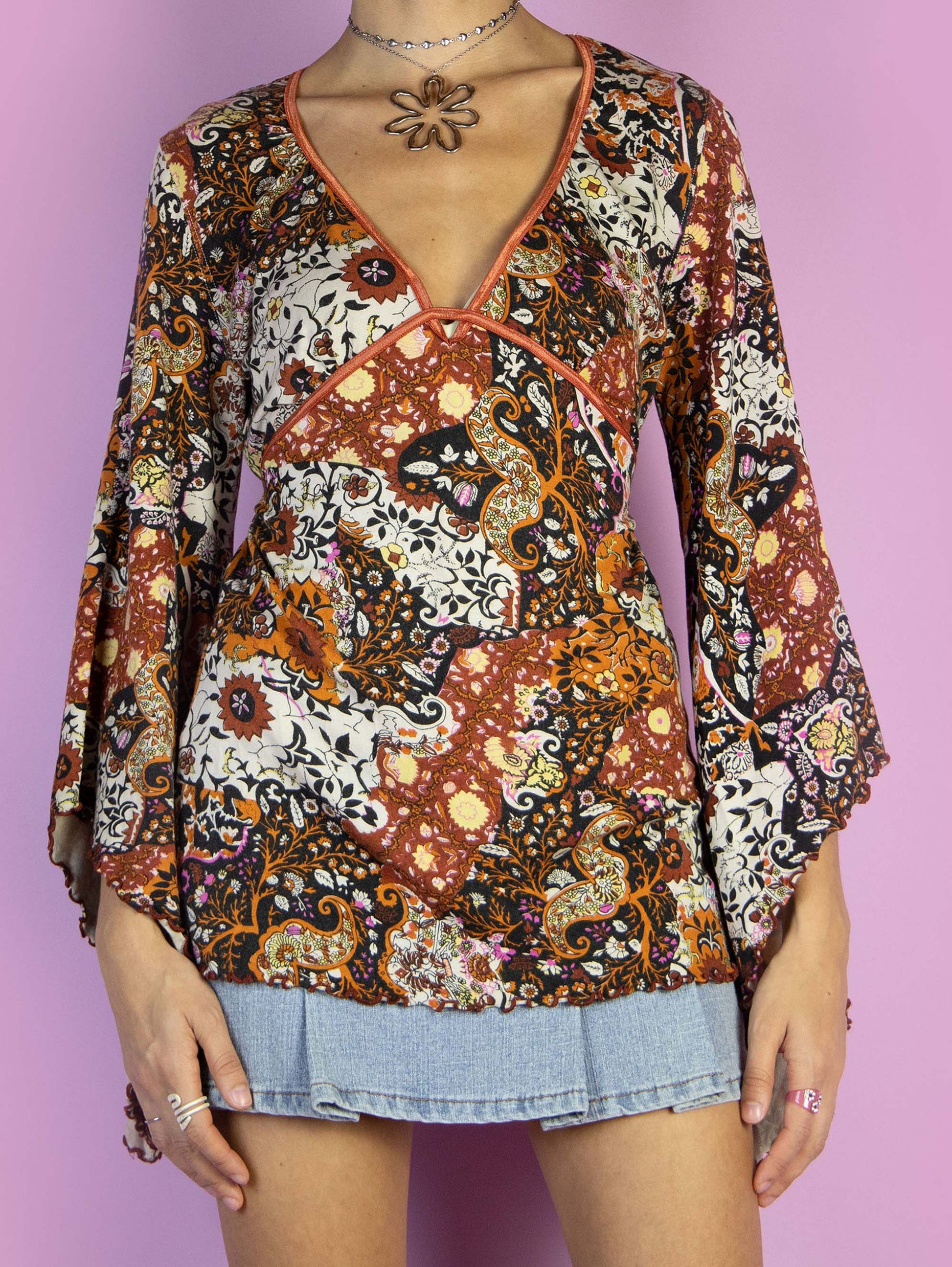 The Y2K Boho Bell Sleeve Top is a vintage multicolored orange top with an abstract paisley floral print, a V-neck, and ties at the back. Cyber fairy grunge 2000s graphic blouse.